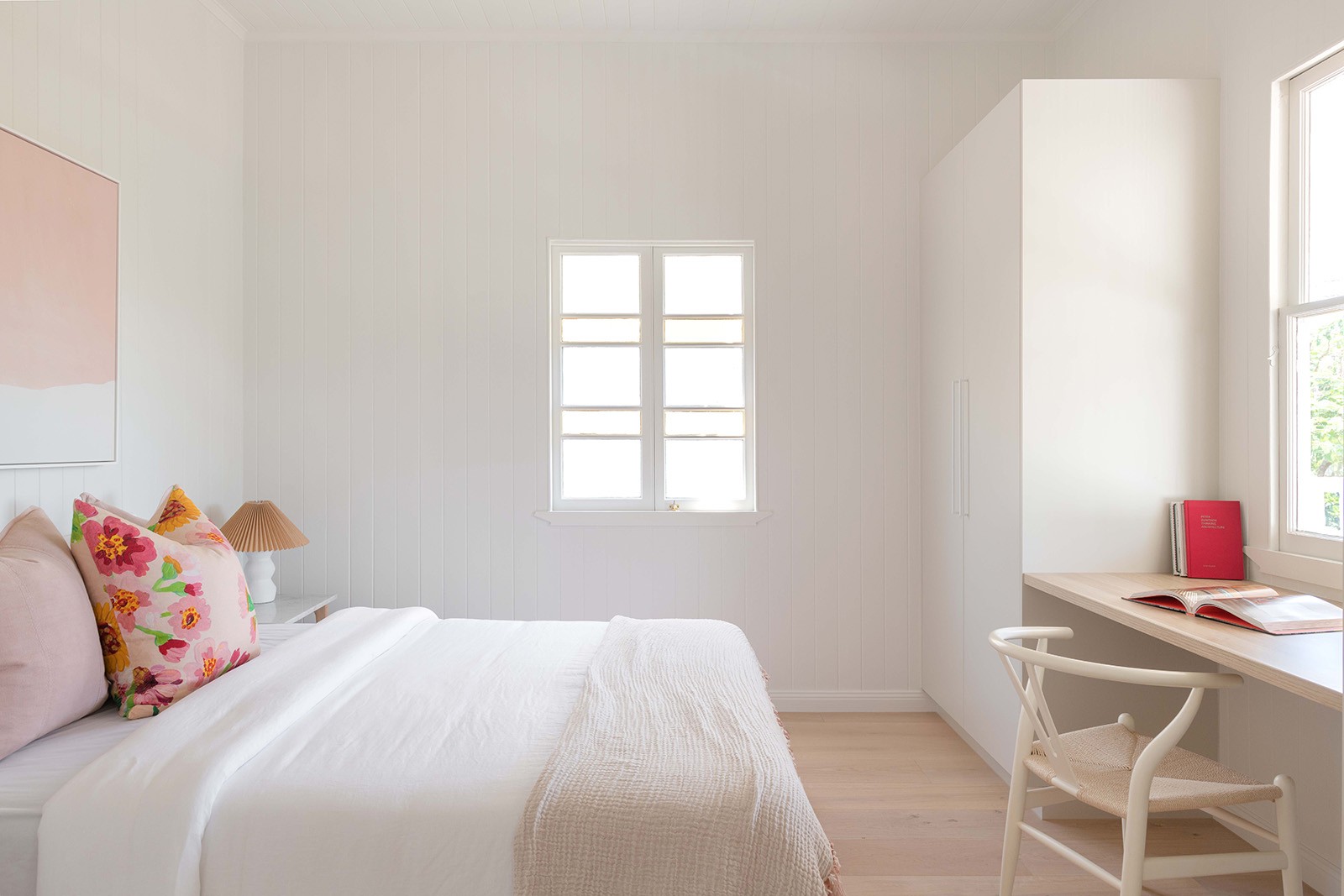 Bedroom at The Stables with soft white finishes, built-in desk, and natural light creating a calm, private retreat.