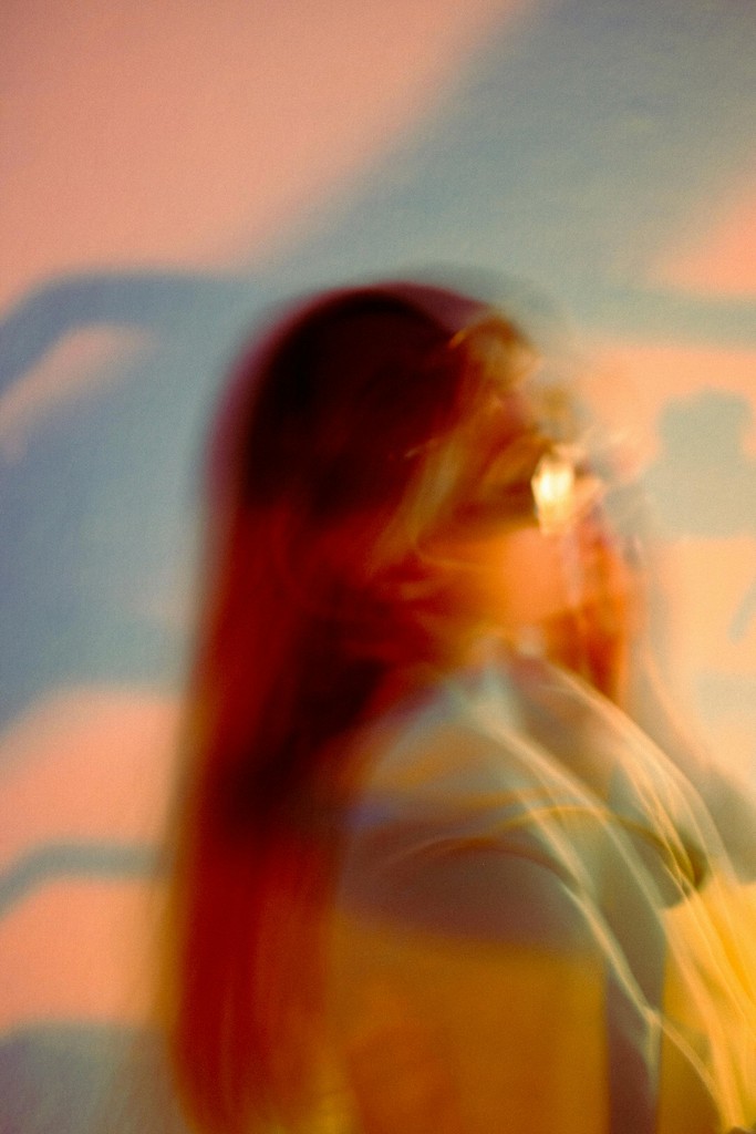 A luxurious bathtub filled with water and floating rose petals, surrounded by candles and greenery. The soft lighting creates a tranquil and romantic spa-like atmosphere.