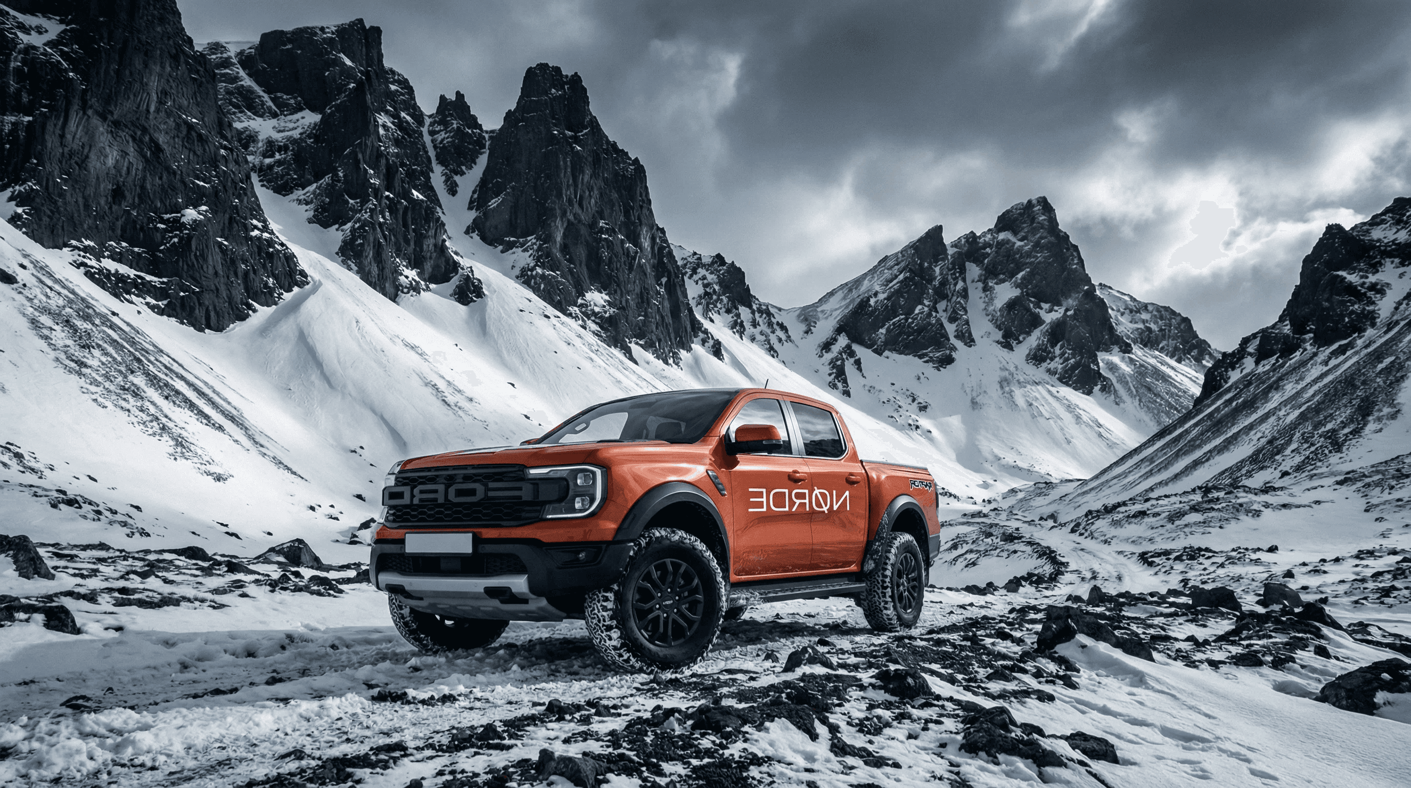 An orange Ford Ranger Raptor pickup truck parked on a snowy, rocky landscape with dramatic mountains in the background.