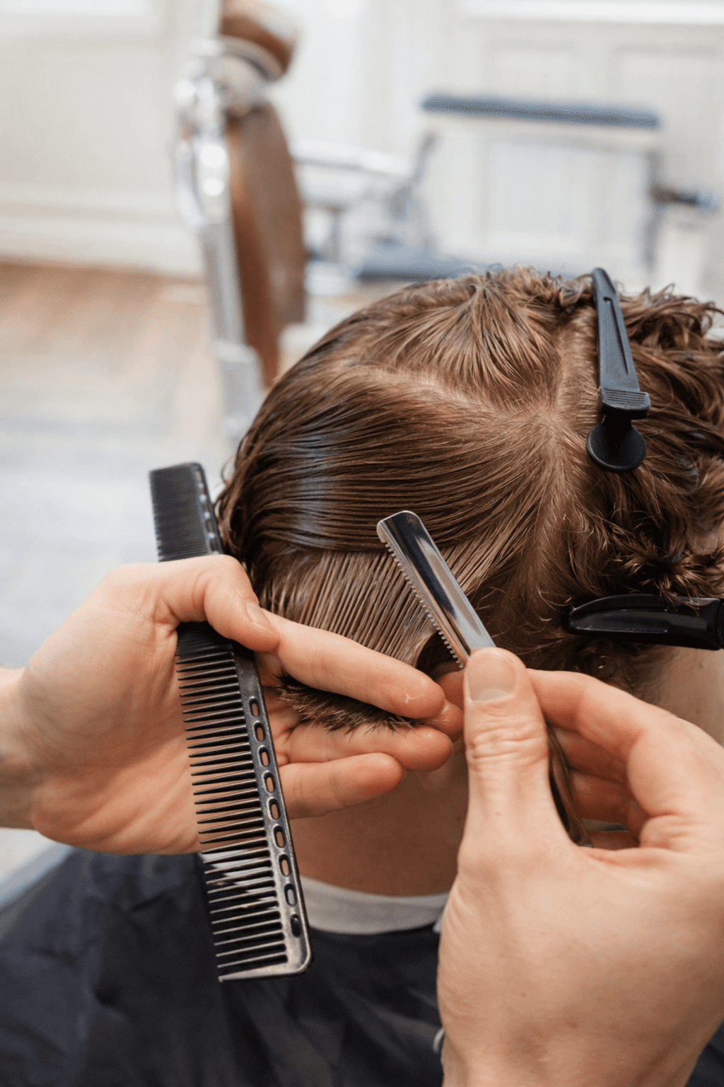 Barber holding clippers and comb near a man's hair