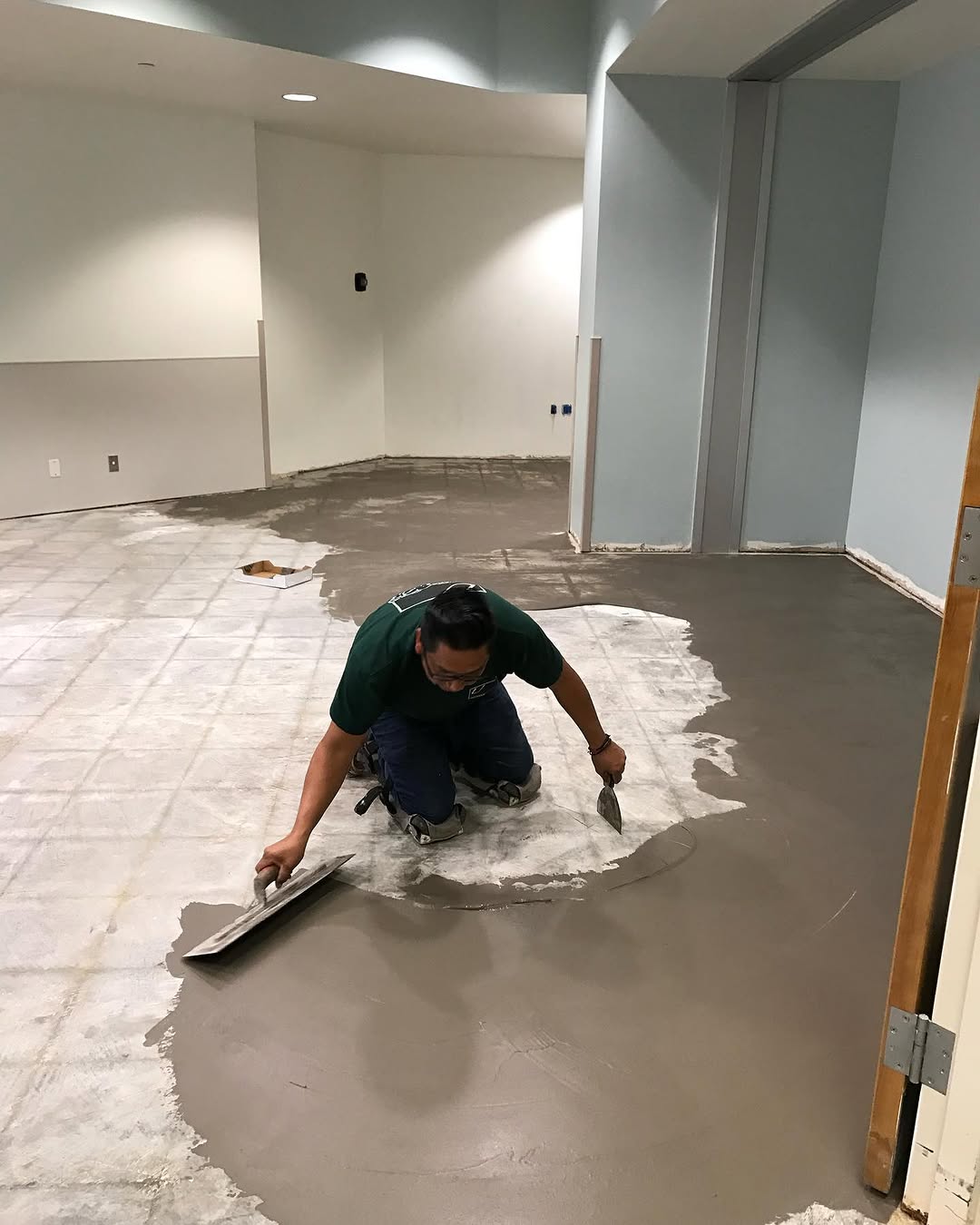 Installer troweling self-levelling compound across a break room slab