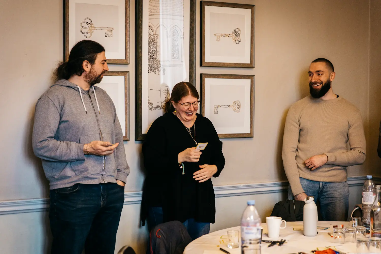 Three people talking at a table with drinks.