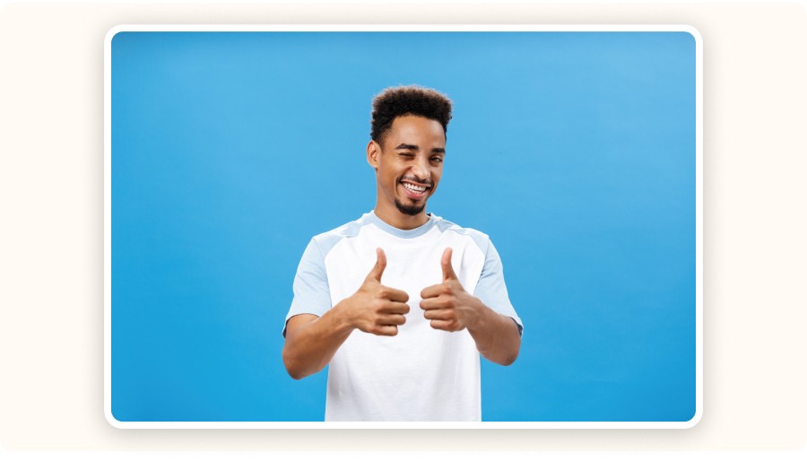 Man smiling and giving thumbs up against blue background&nbsp;