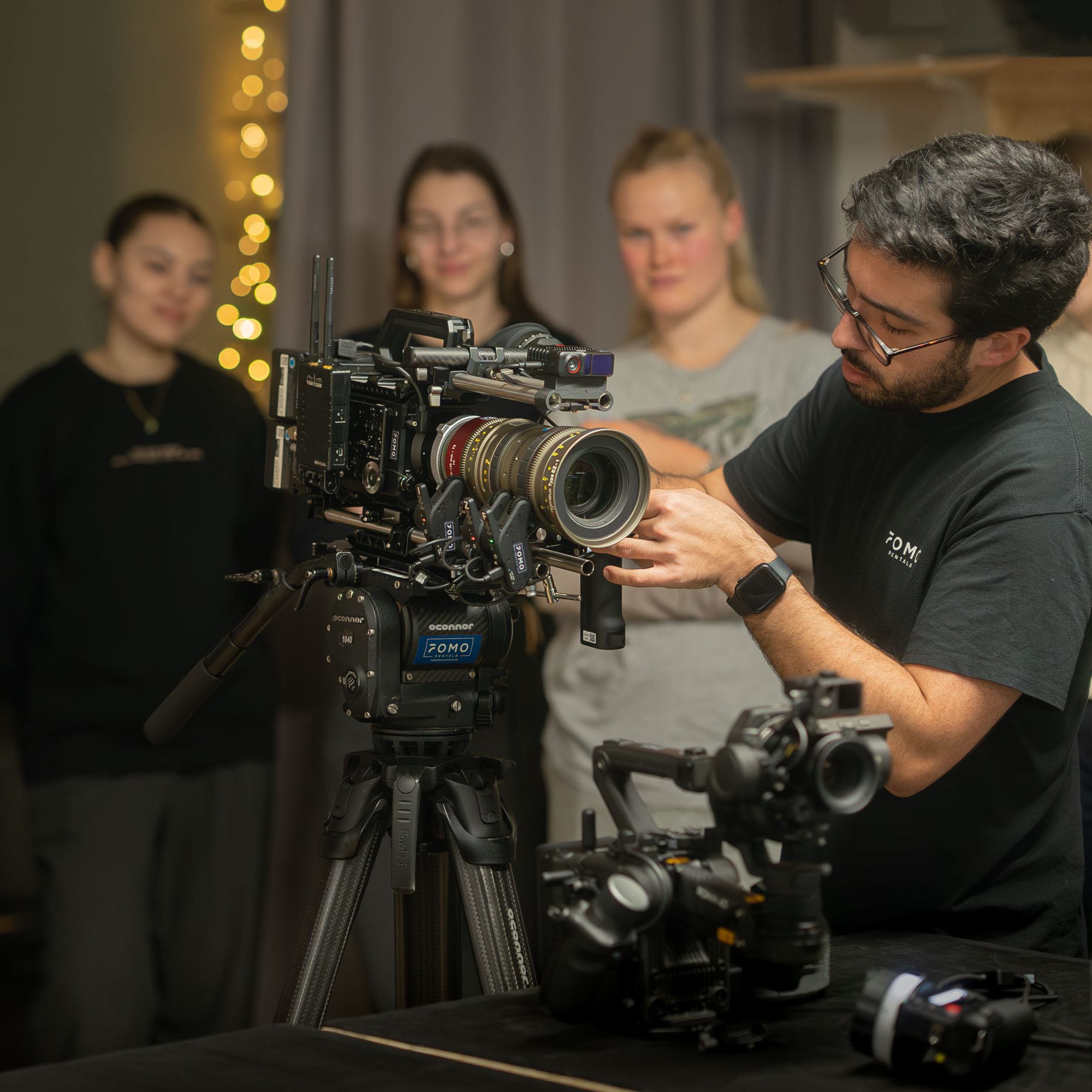 A FOMO technician checking a zoom lens on a camera build