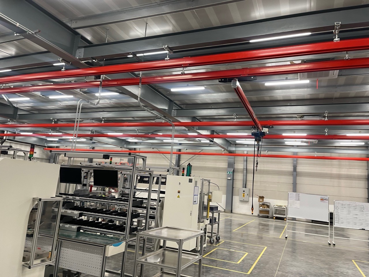 Factory workshop interior with overhead crane rails, linear LED industrial ceiling lights above production equipment