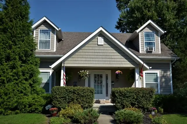 Cozy suburban house with a gabled roof, front porch, and well-kept garden.