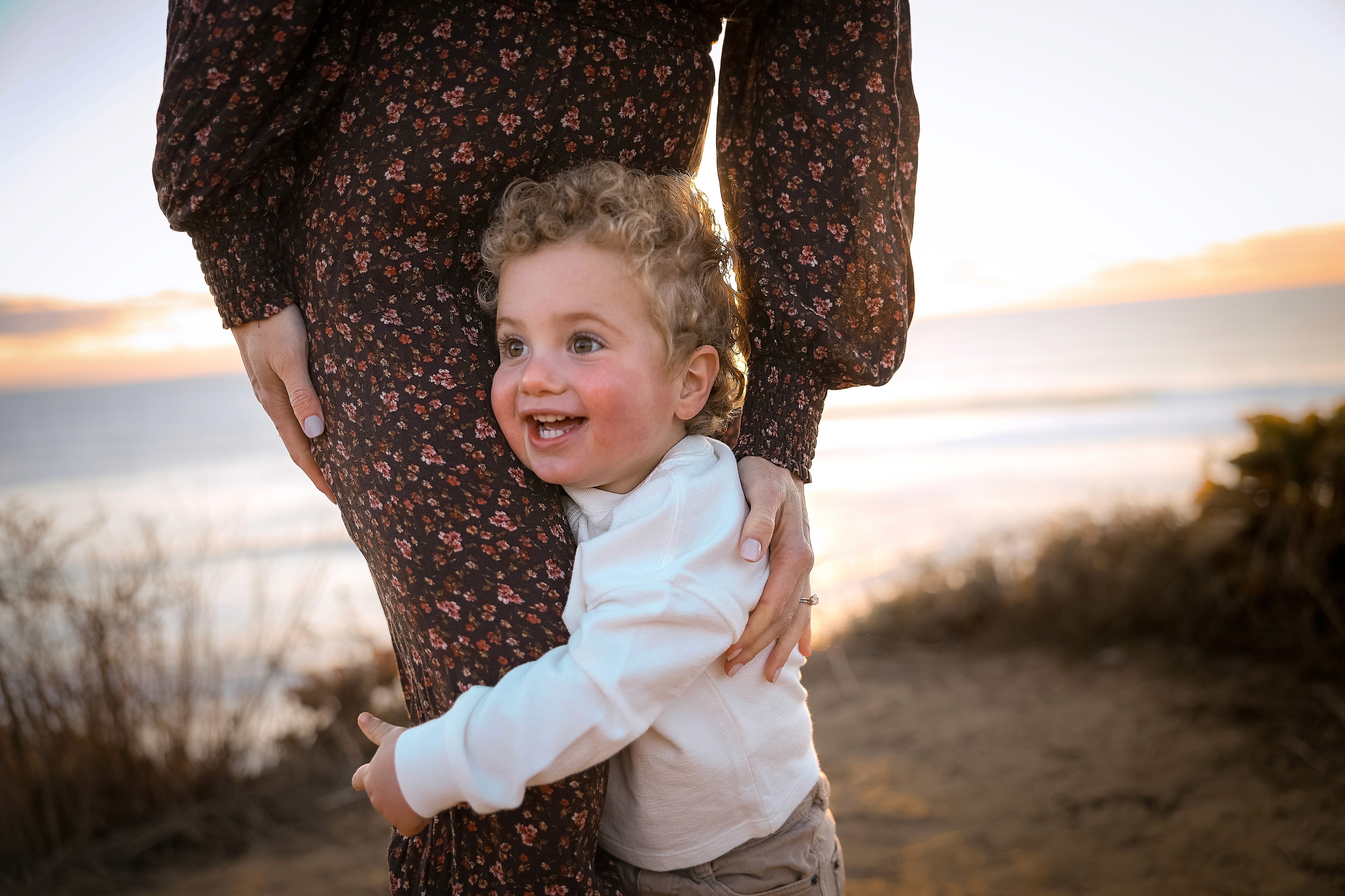 Mother and child looking at the ocean at sunset during a warm family session.