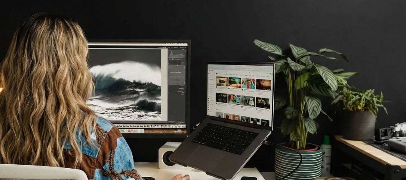 Photographer editing images at a desk with dual monitors in a home studio workspace using generative AI