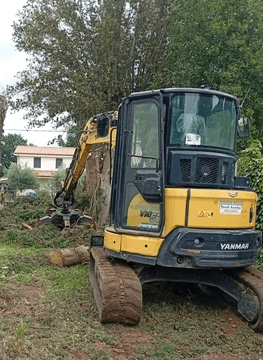 mezzo cingolato con pala idraulica lavora la terra per rimuovere radici in giardino di bracciano
