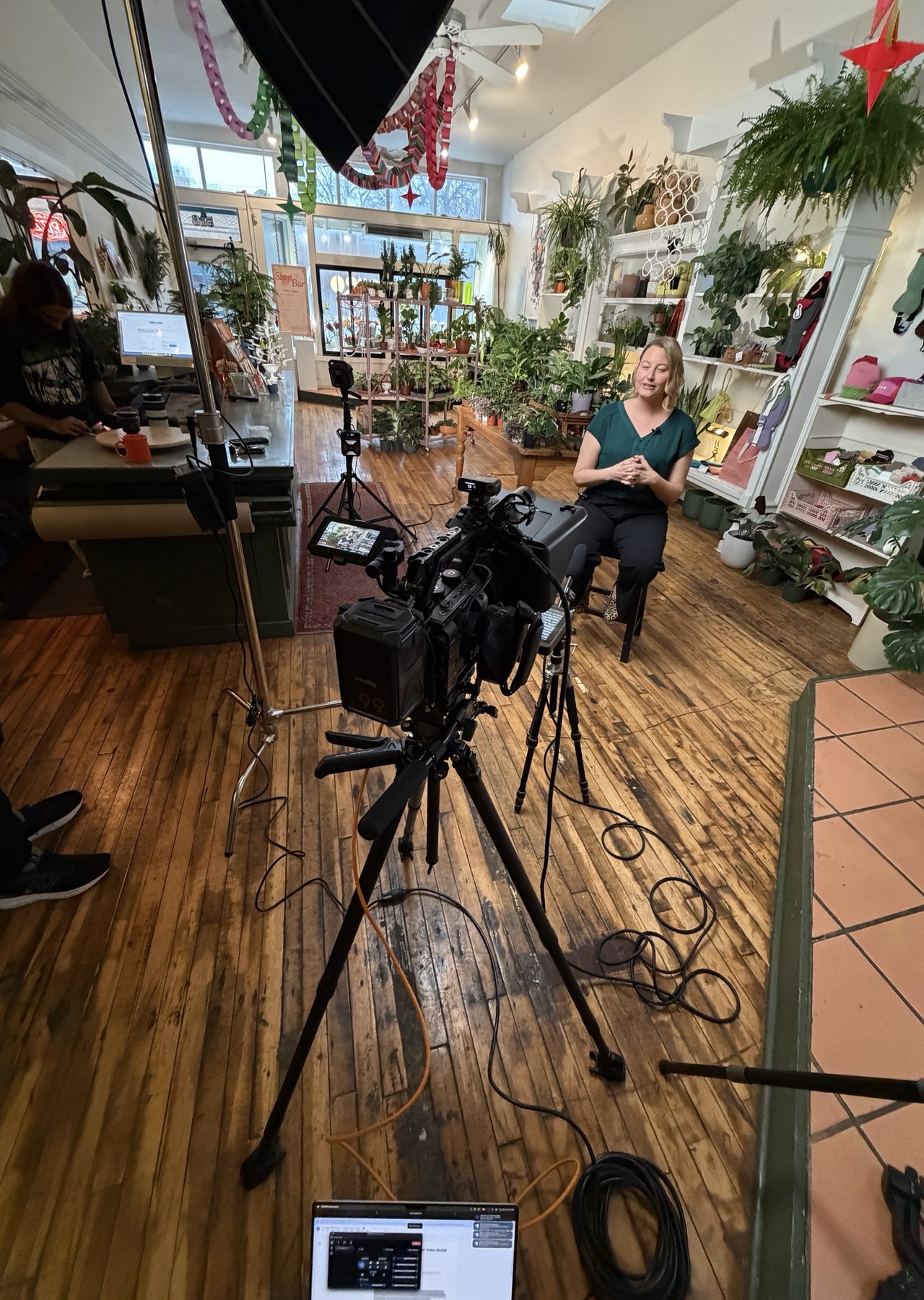 Filming a seated interview inside a plant shop, camera and lights on tripods
