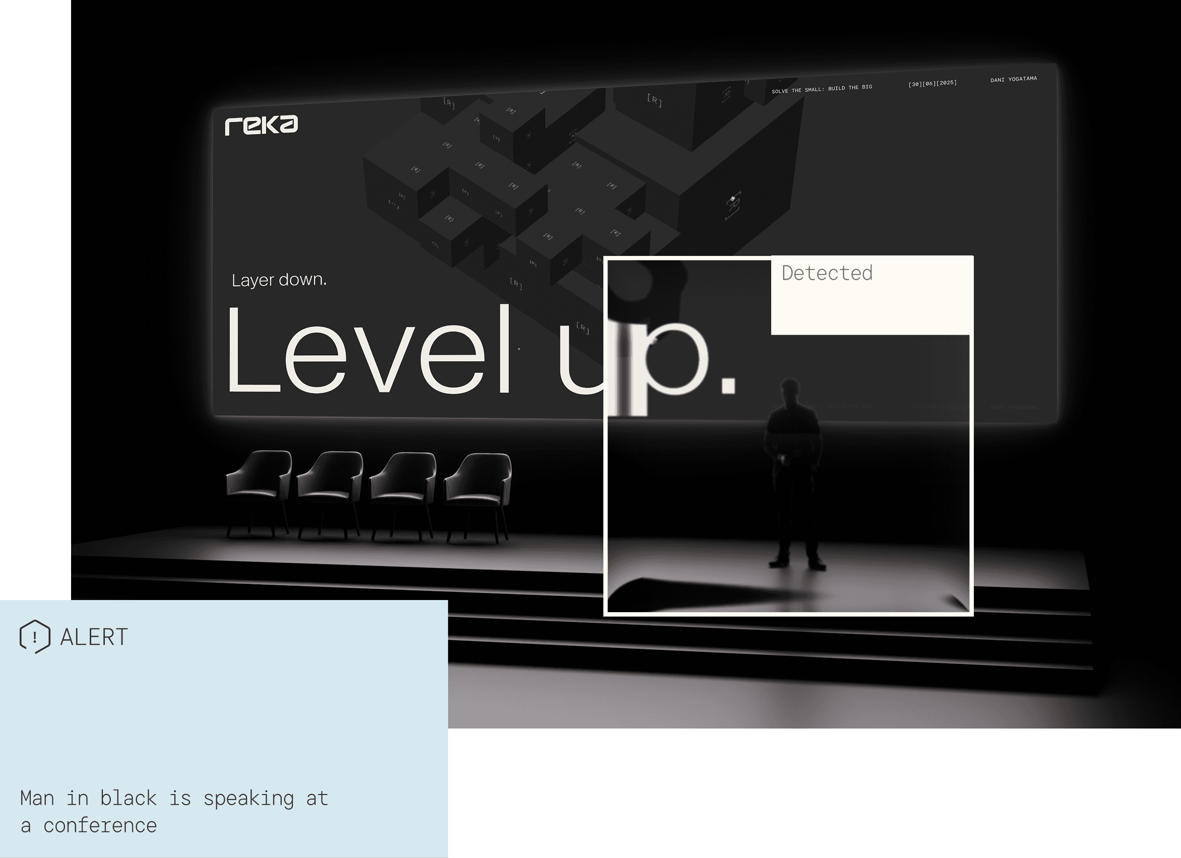 A conference stage with a large screen displaying "Layer down. Level up." under the Reka logo. An AI detection overlay identifies a "Man in black speaking at a conference" on the stage.