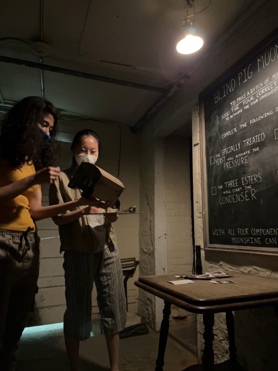 Two players test the physical props and wall clues inside the Casa Loma escape room.