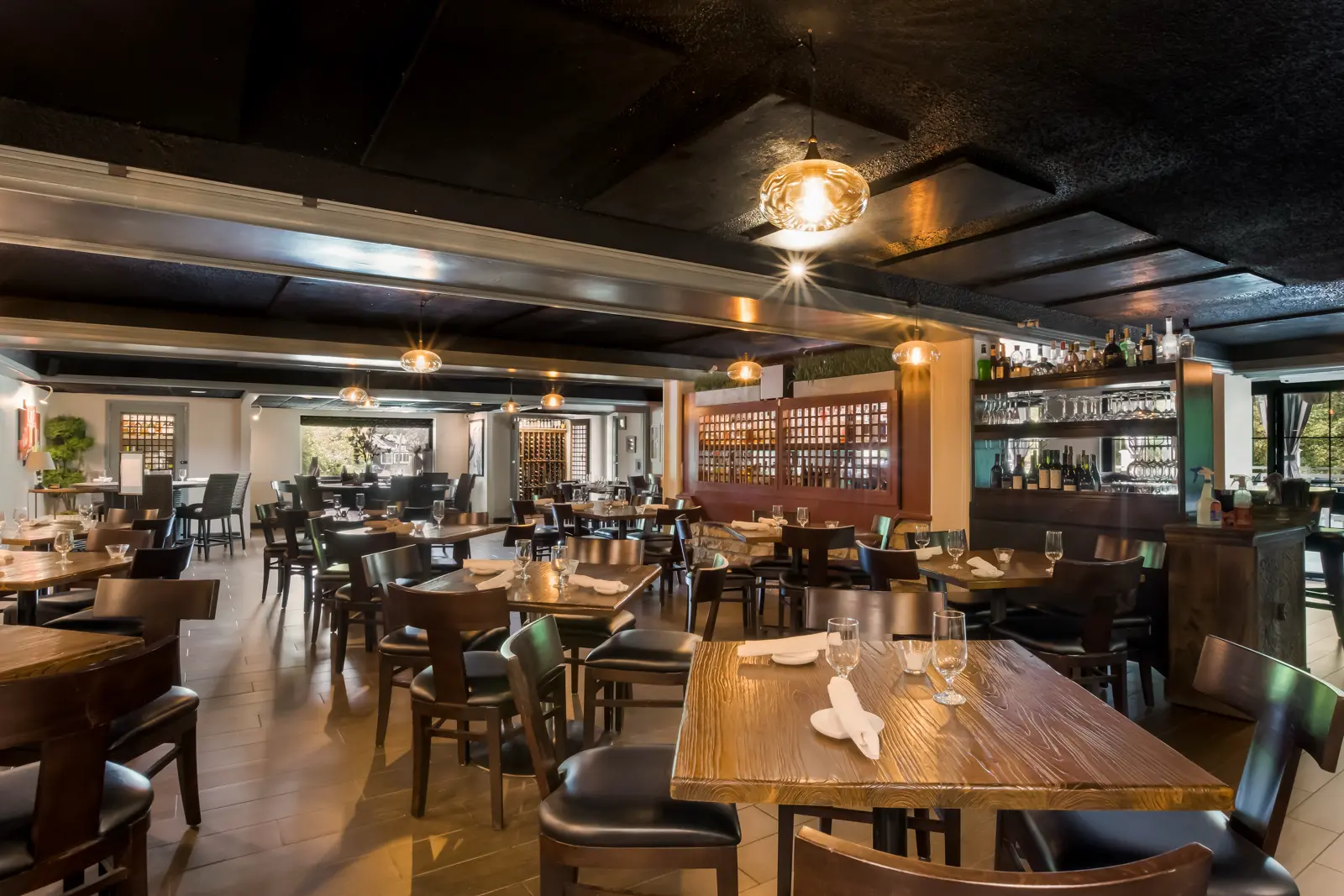 Empty restaurant dining room with set tables and a bar.