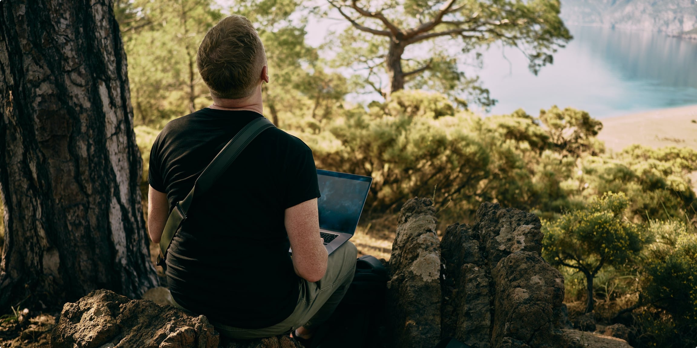 Decorative image of a man on his back in a natural setting holding a laptop computer on his lap.