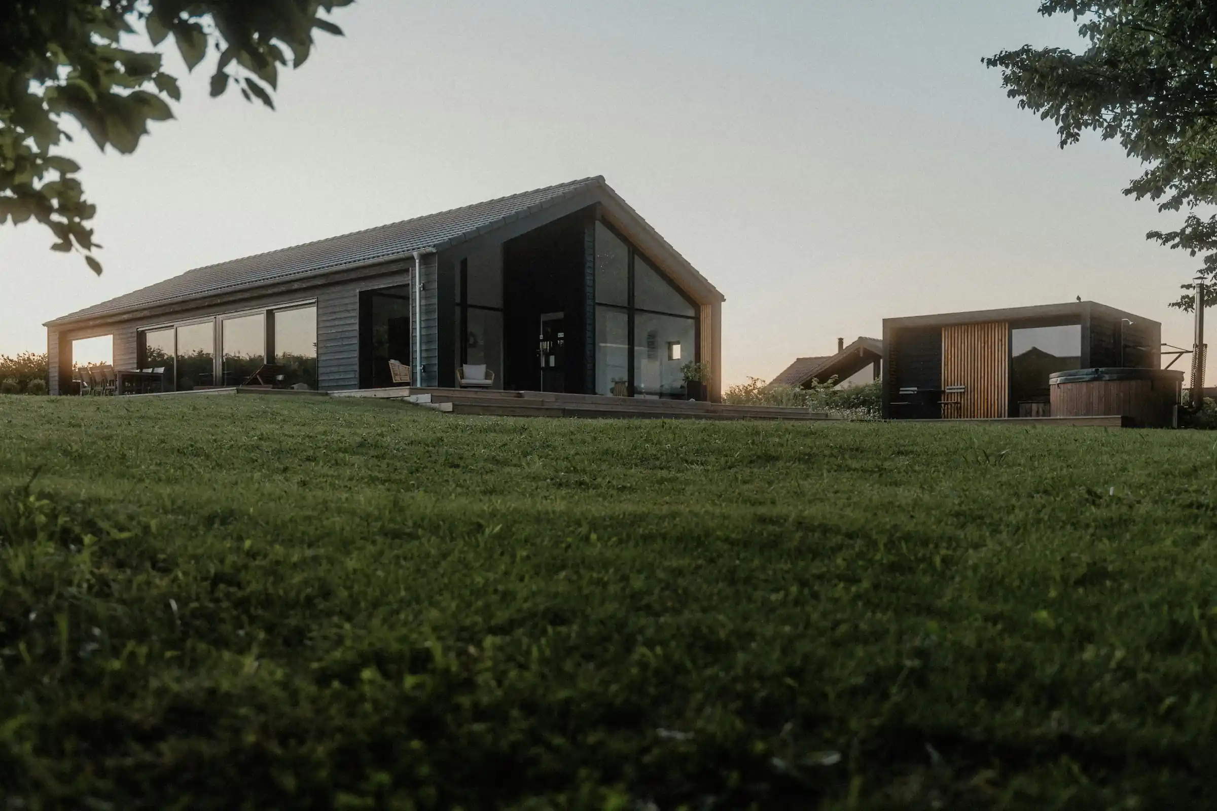 Minimalist living space featuring oak flooring, timber wall panels and panoramic windows with natural light.