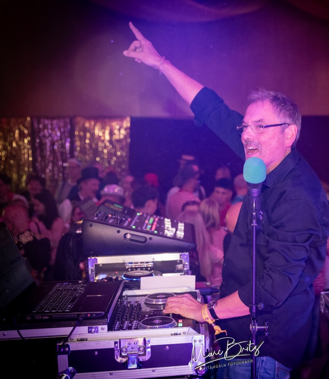 DJ hinter Mischpult in Aktion mit stimmungsvoller Haltung. Tanzende Menschen. 