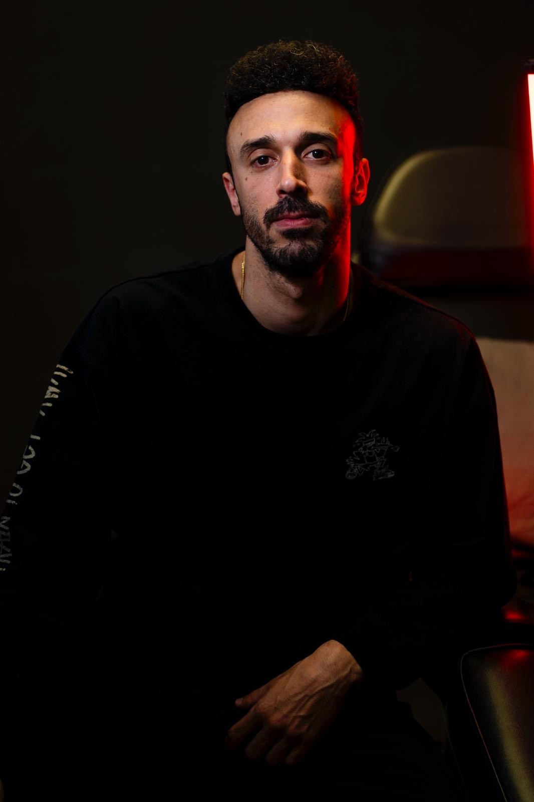 A thoughtful young person with dark hair gazes to the side, captured in soft black and white lighting.