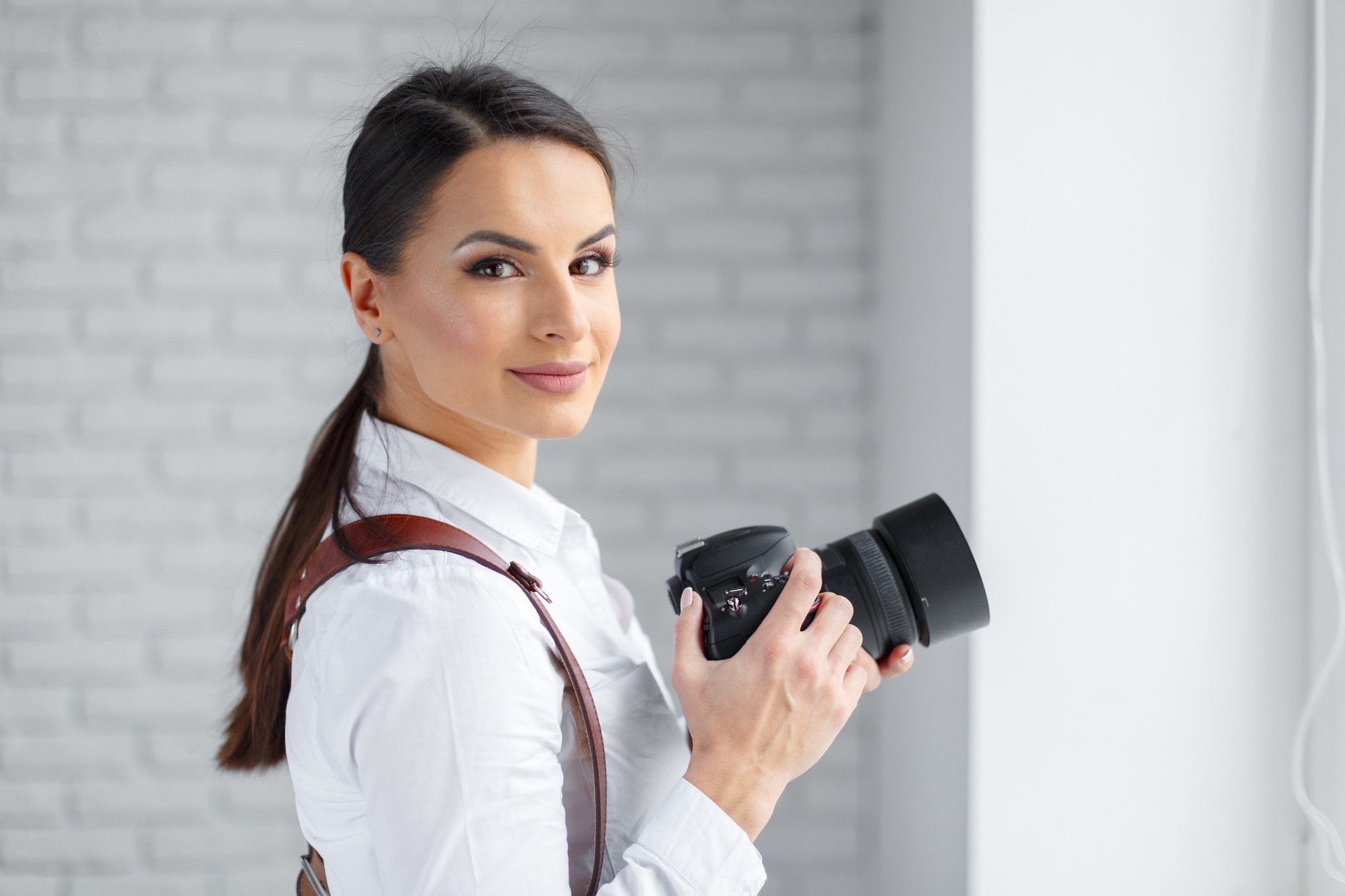Professional wedding photographer with DSLR camera and leather strap in studio