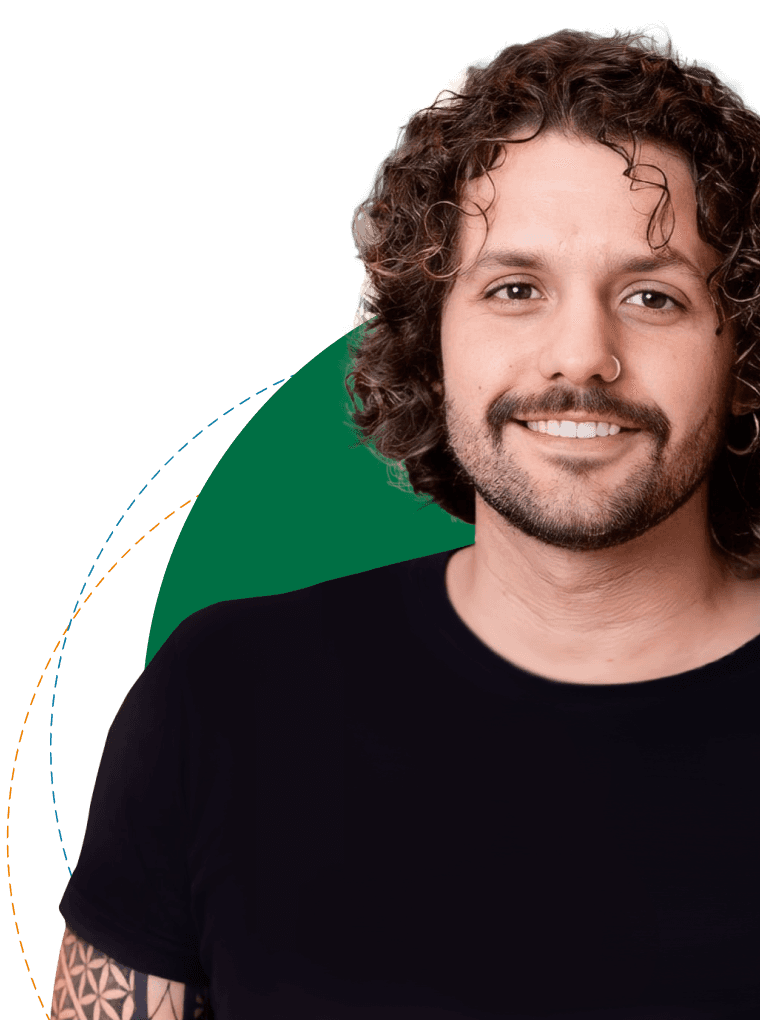 Léo Formigon, homem de cabelo castanho cacheado, médio volume e na altura do pescoço, barba leve, utilizando uma camiseta preta, sorrindo e posicionado de frente para a câmera, levemente inclinado para a esquerda da tela.