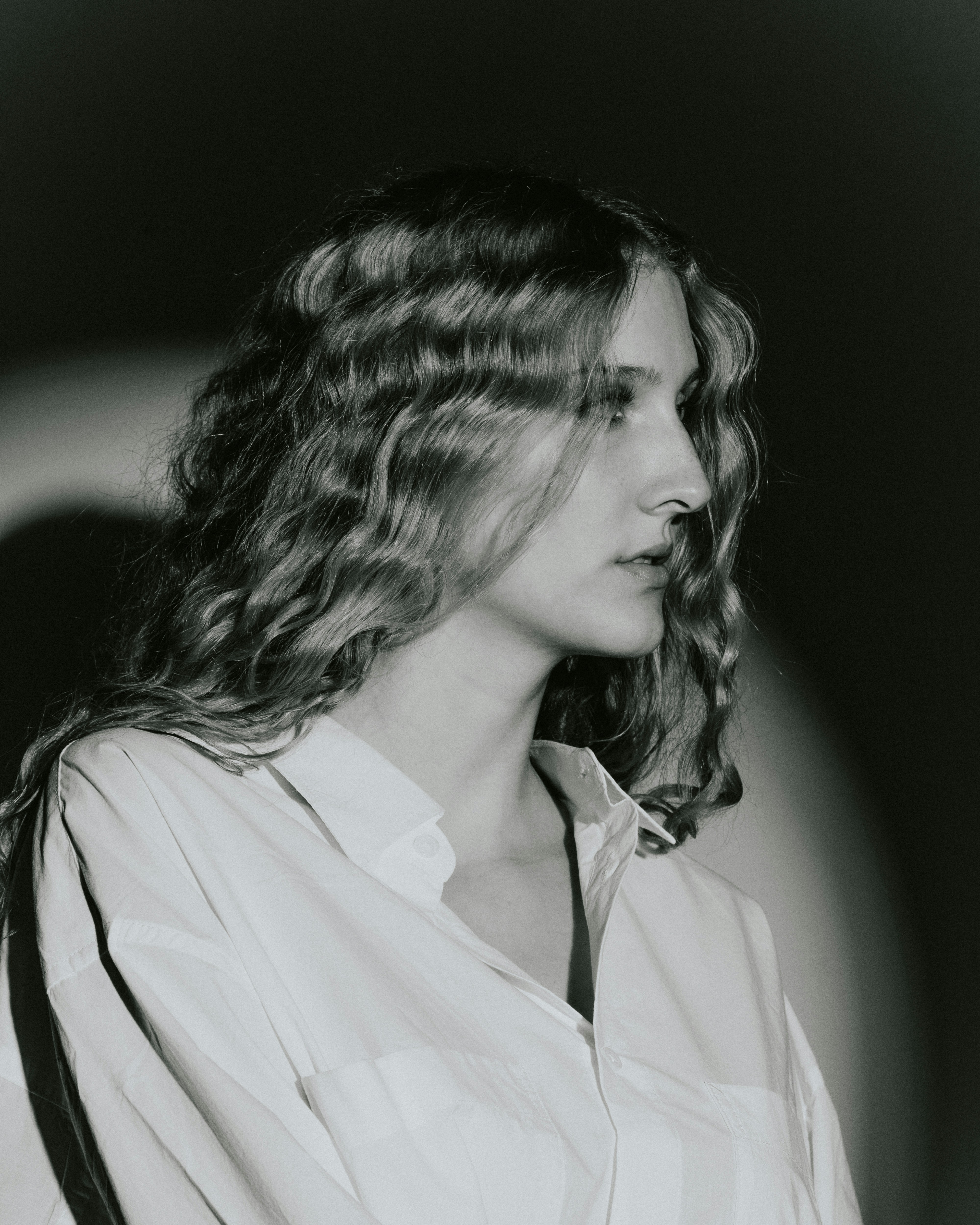 A woman with wavy hair is looking to the side.