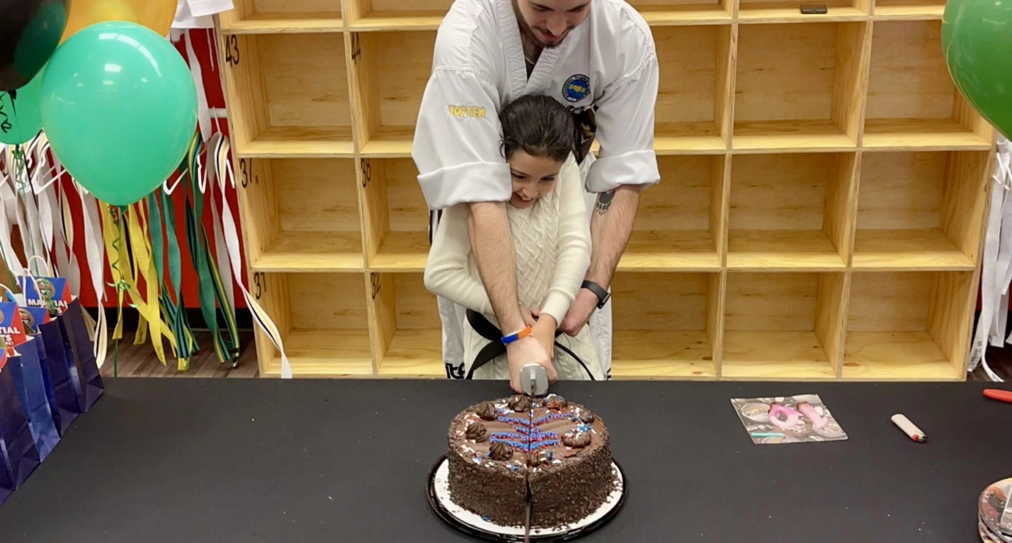 Child being helped with cutting birthday cake with a sword.