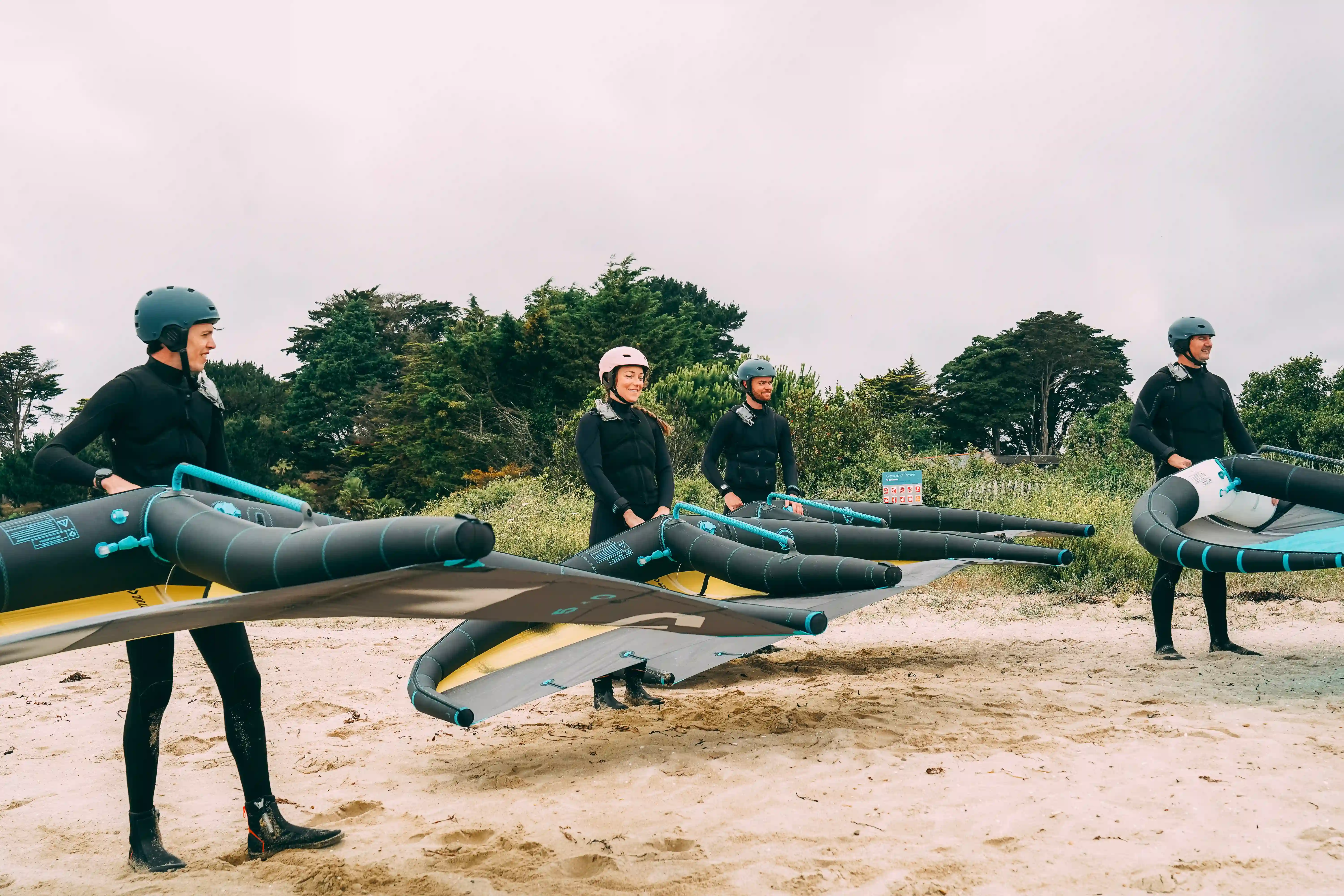 élèves en stage de wingfoil sur la plage tenant leur voile