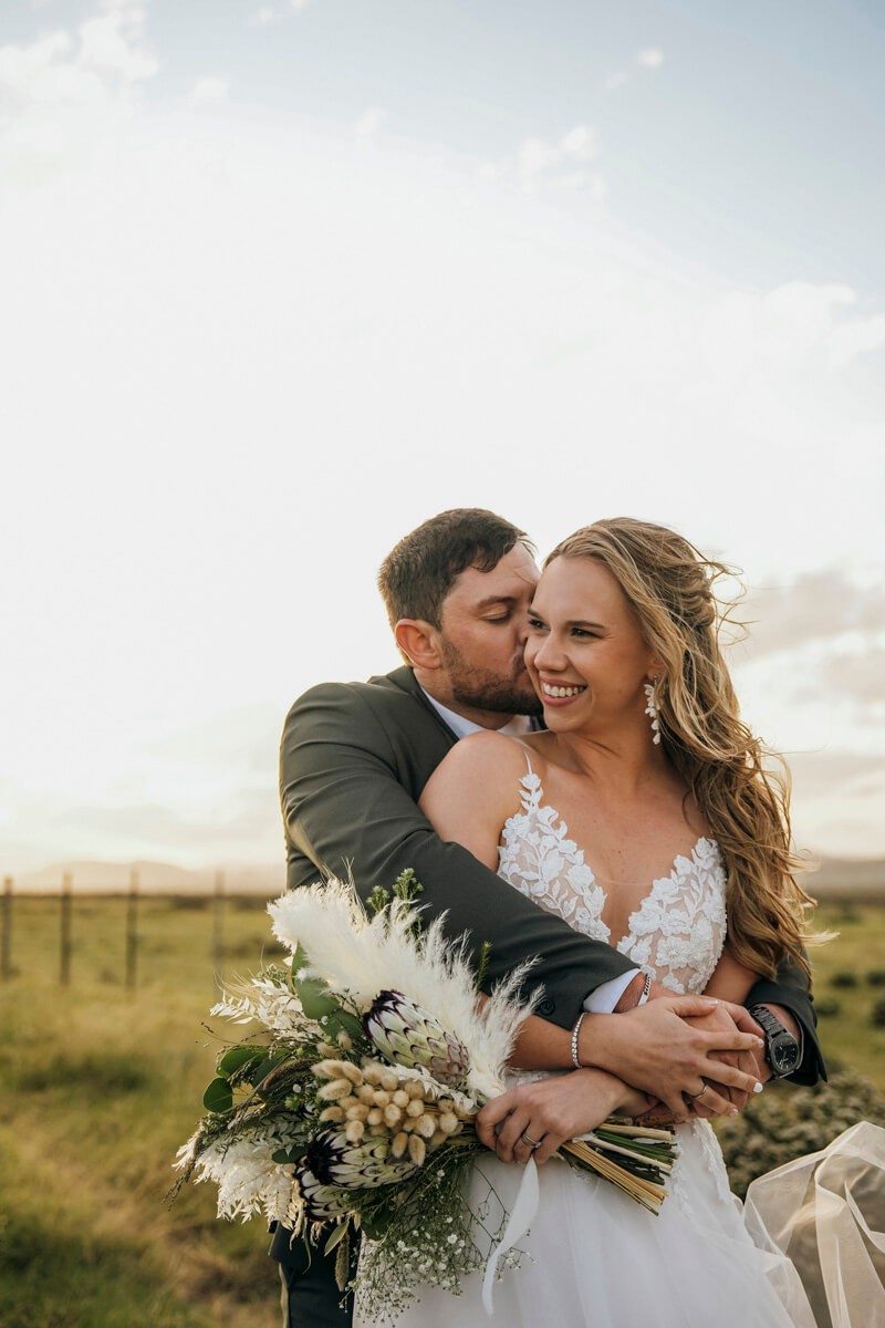Groom embracing bride from behind during emotional wedding portrait