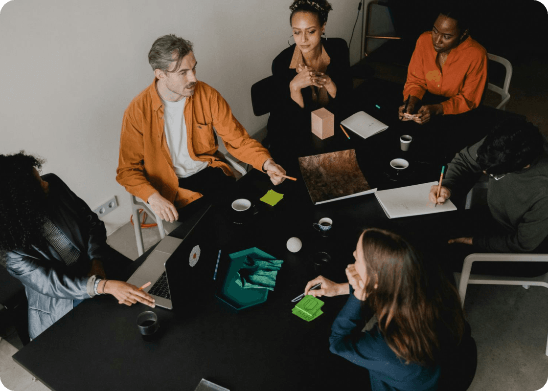 A diverse group of individuals collaborating around a table, each engaged with their laptops in a productive environment