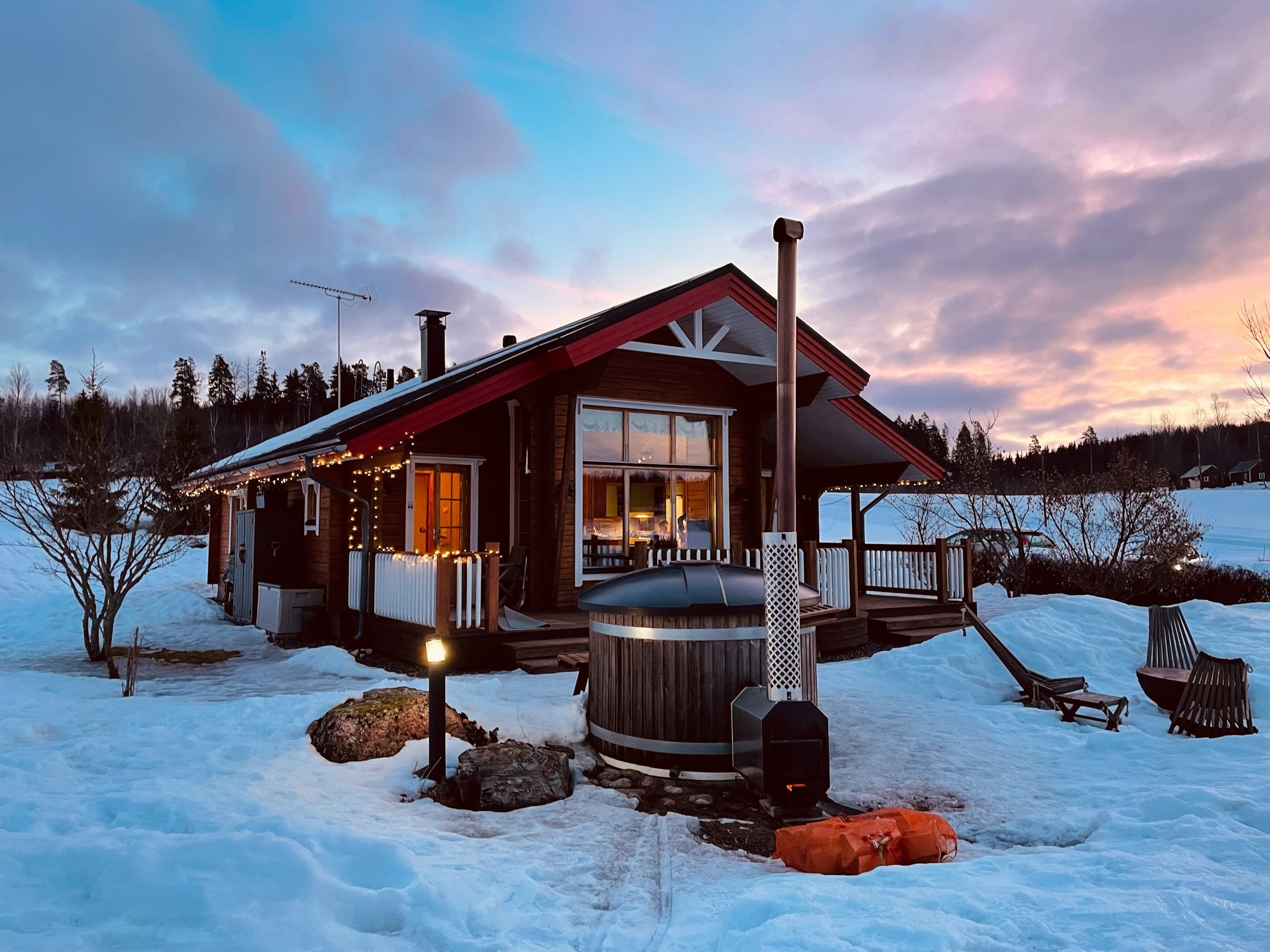 Wooden hot tub  in a snowy landscape at sunset