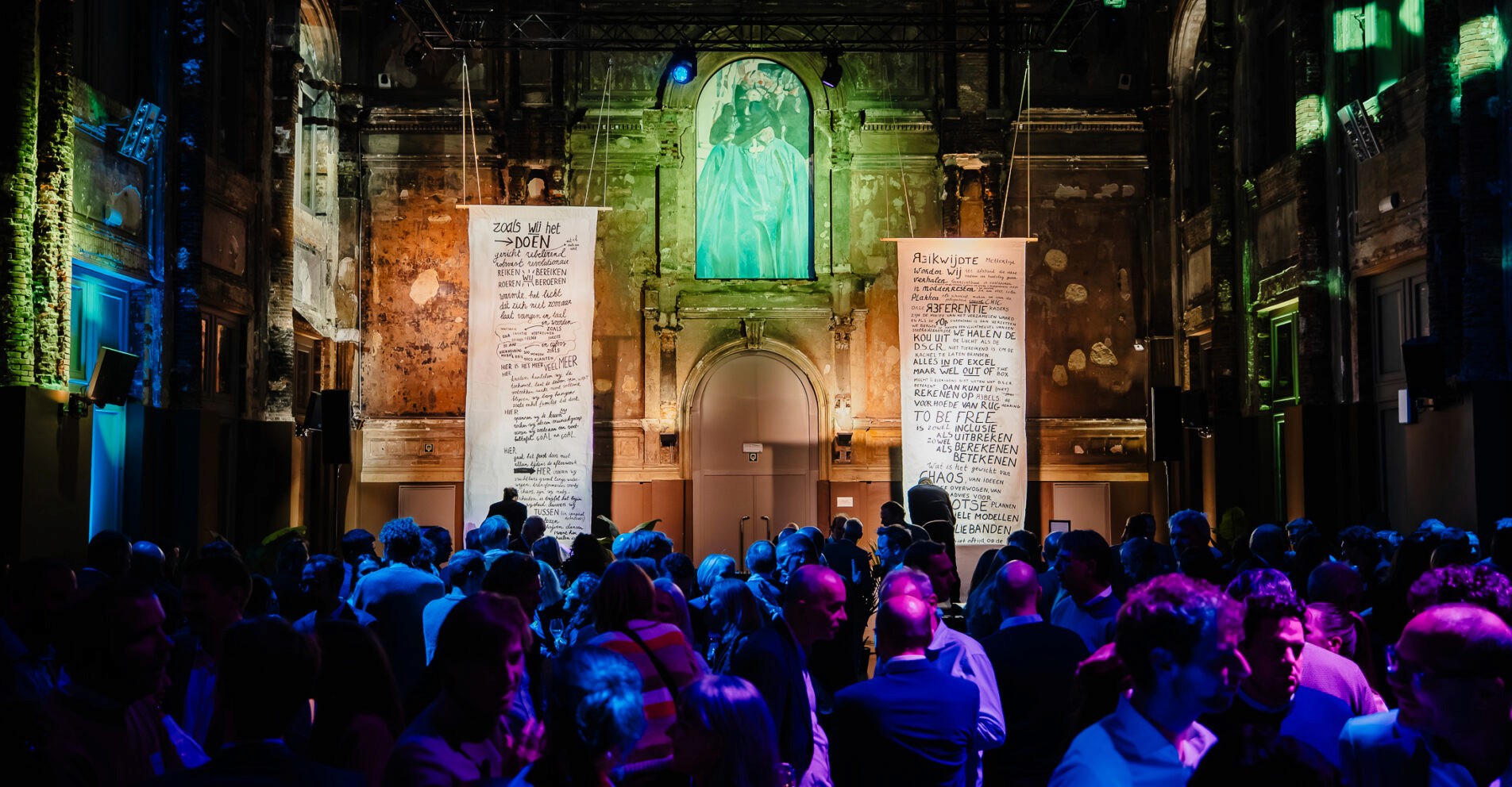 Groep gasten geniet van evenement in monumentale zaal met creatieve lichtshow, verzorgd door Kibo Events.