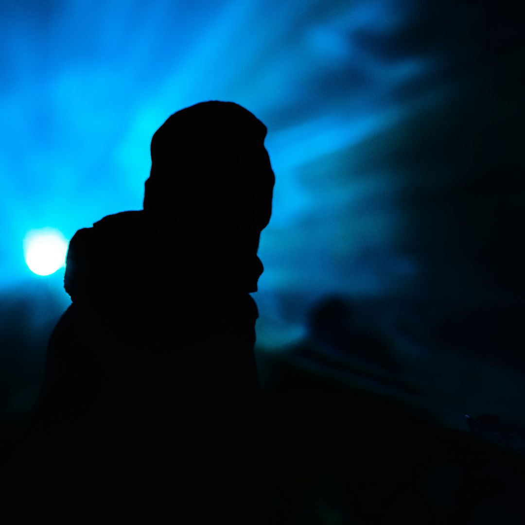 A person in silhouette against a burst of blue light