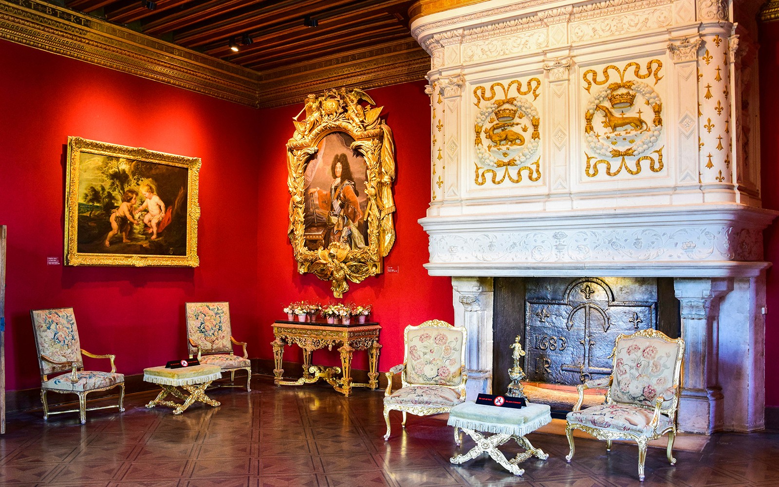 Interior del Château de Chenonceau con chimenea ornamentada, paredes rojas y pinturas clásicas, Valle del Loira.