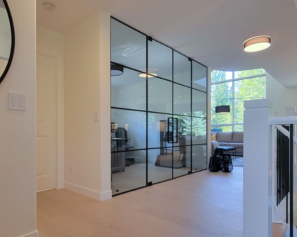 An interior room with floor to ceiling glass with black metal accents.