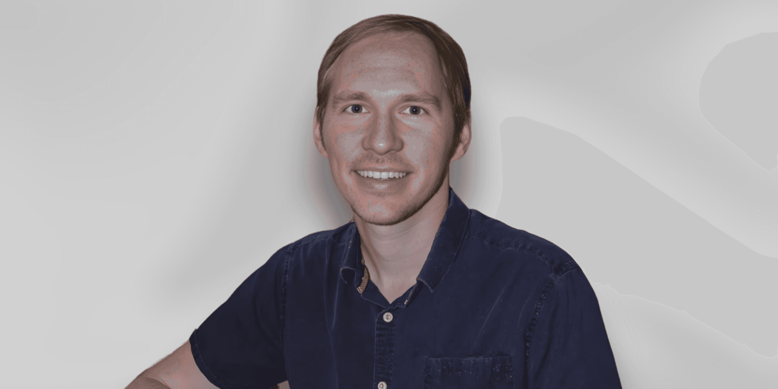 A smiling man in a blue shirt, embodying warmth and positivity, represents family cooperation and growth.