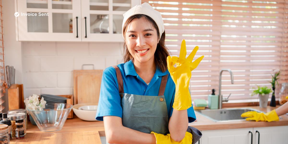 a woman in a green shirt and black gloves vacuuming a gray ottoman