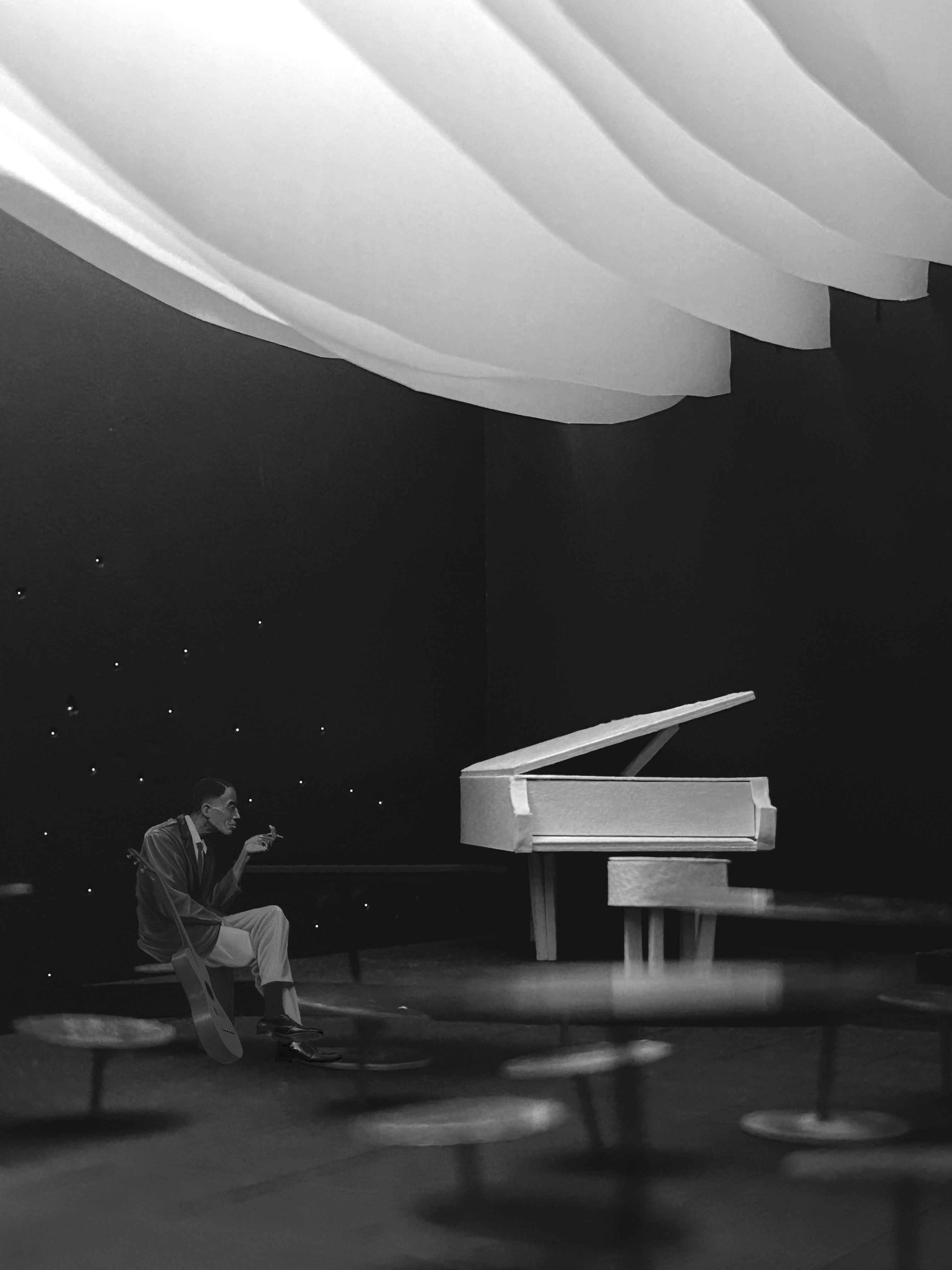 A spacious indoor café with wooden floors, large windows, plants, and a mix of seating areas and workspace.