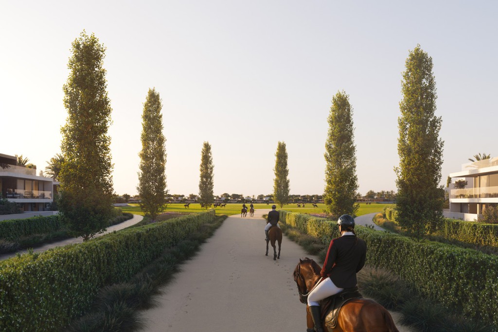 A man riding a horse along a tree-lined path at Equiterra at Grand Polo.