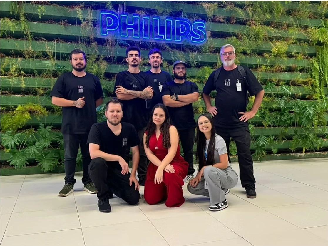 Equipe da Casa Oito diante do letreiro da Philips em parede de jardim vertical
