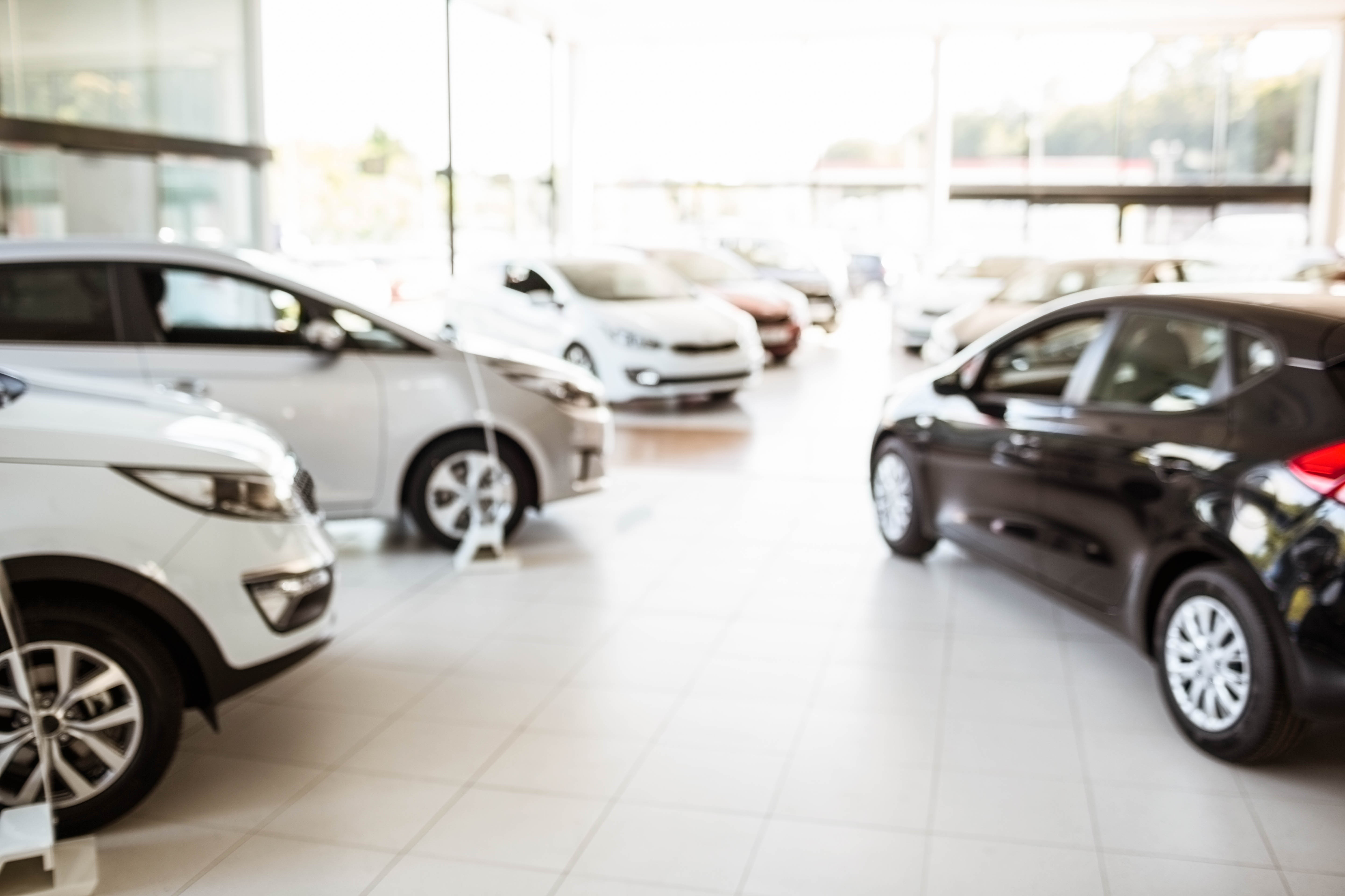 Cars in a dealership showroom. Bright, modern. Buying a new car