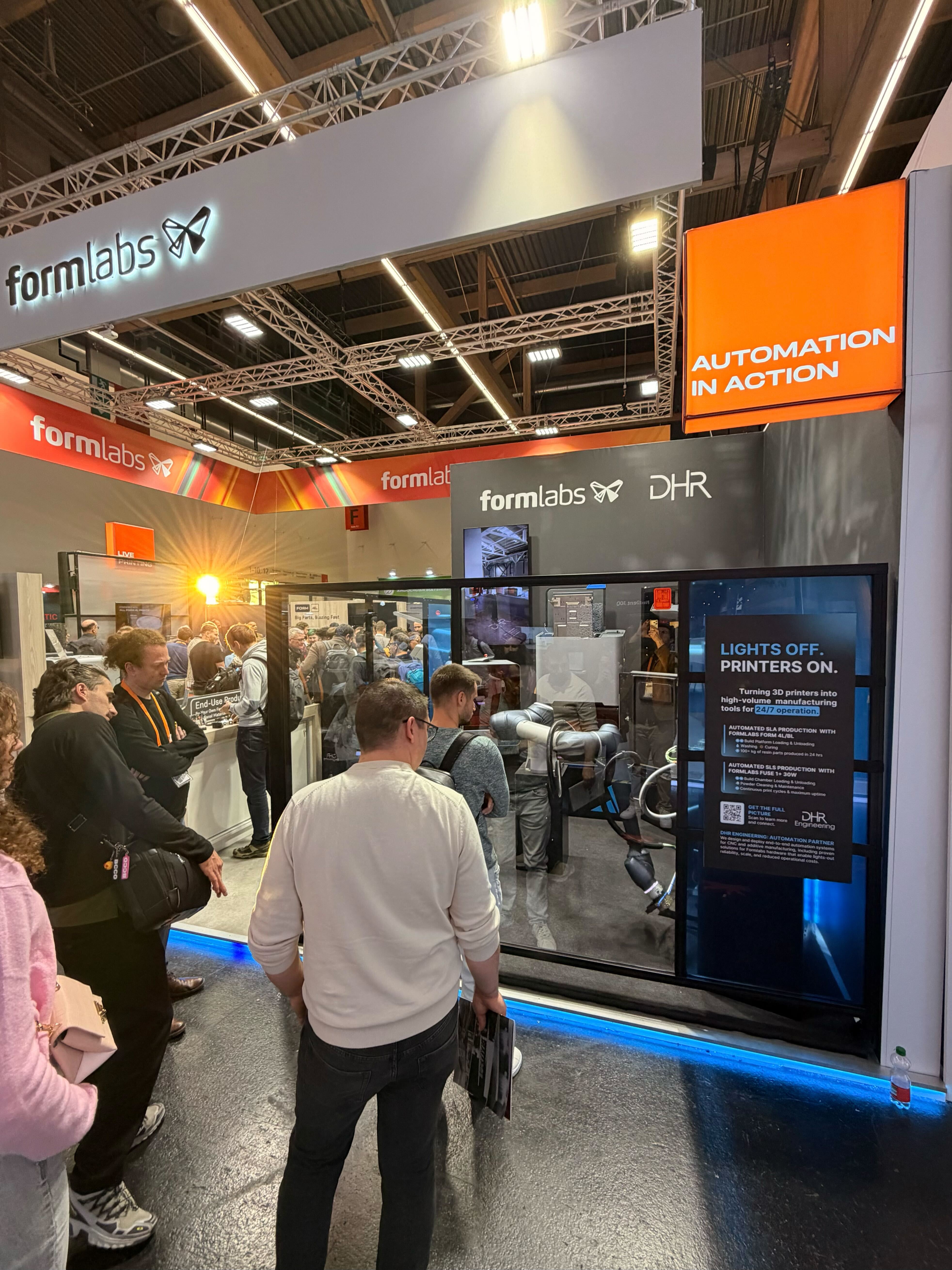 DHR's automated 3D printing SLA and SLS cell at the Formlabs booth with people looking at the demonstration