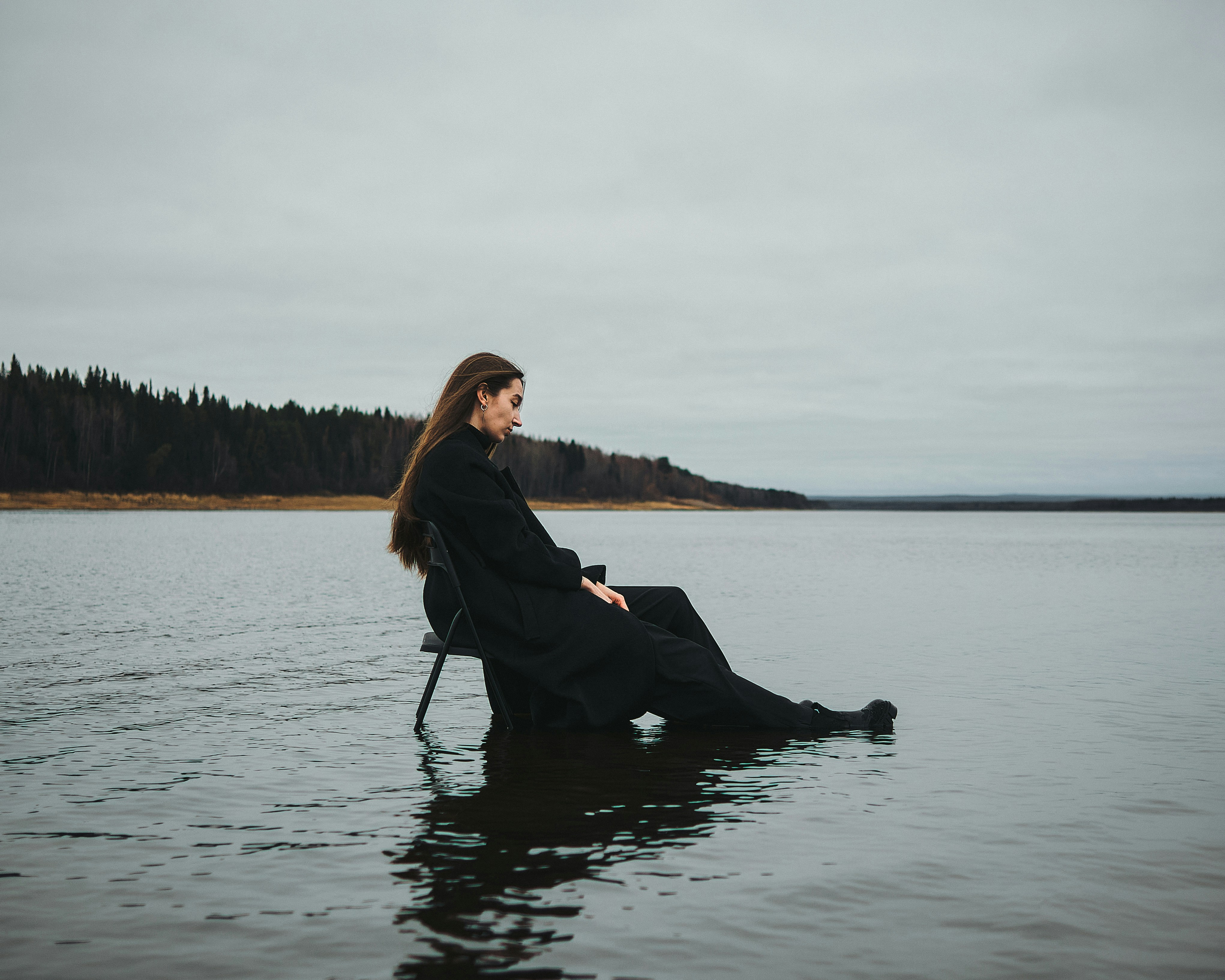 A lady sitting on a chair inside a body of water