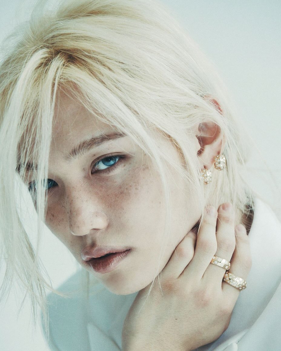 Felix of Stray Kids with platinum blonde hair and freckles, wearing pearl jewelry and a white outfit for Louis Vuitton in ELLE Korea.