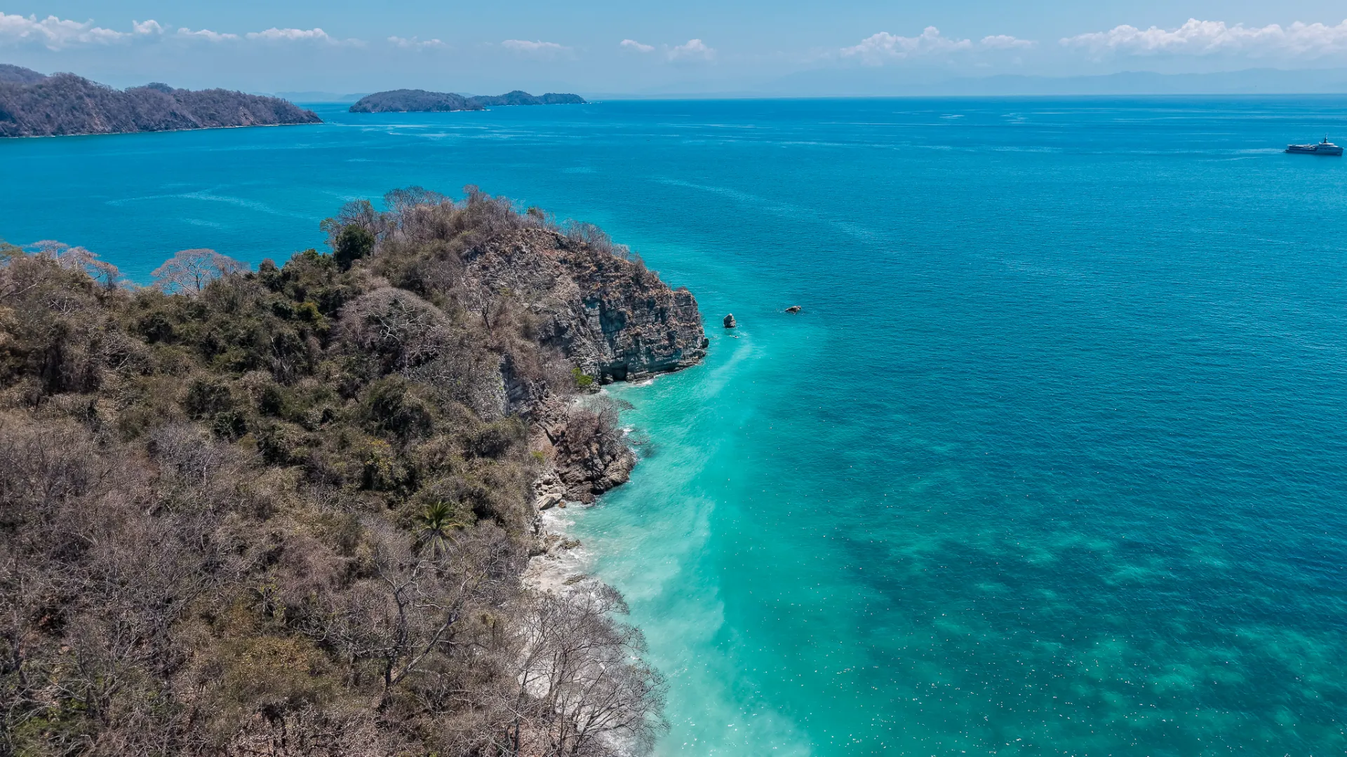 Aerial view of the rocky coast and turquoise water of Isla Tortuga, Gulf of Nicoya, Costa Rica