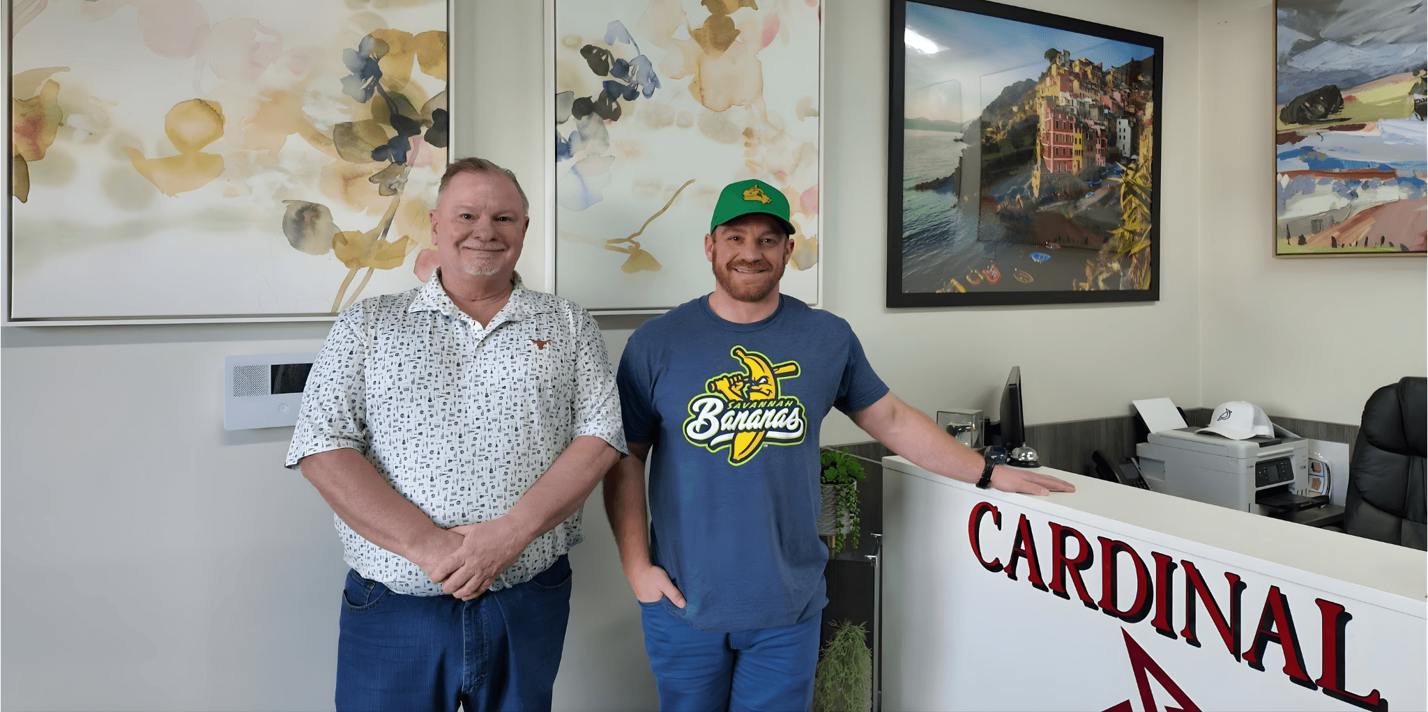 Modern glass and wood cabin with a cozy outdoor deck featuring wicker furniture, surrounded by lush green trees and a serene forest setting.
