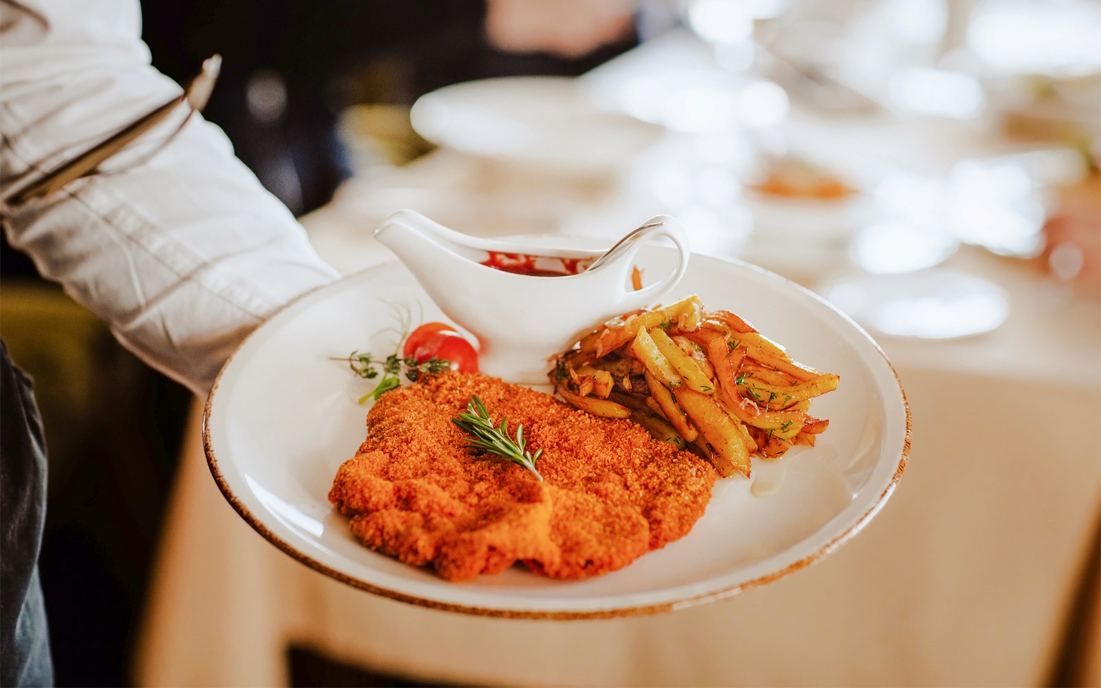 Pelayan menyajikan Schnitzel Wina dengan kentang goreng dan saus.