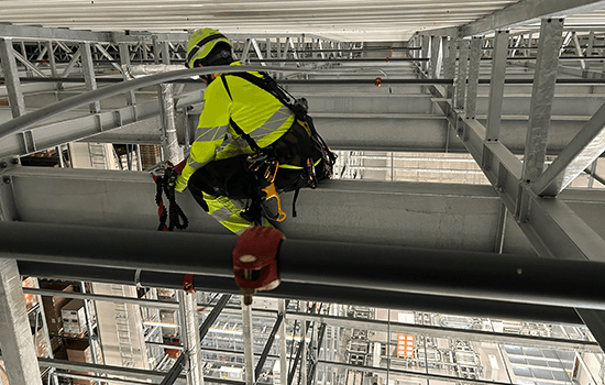 Four diverse professionals collaboratively working on a laptop, with one person pointing at the screen while others observe.