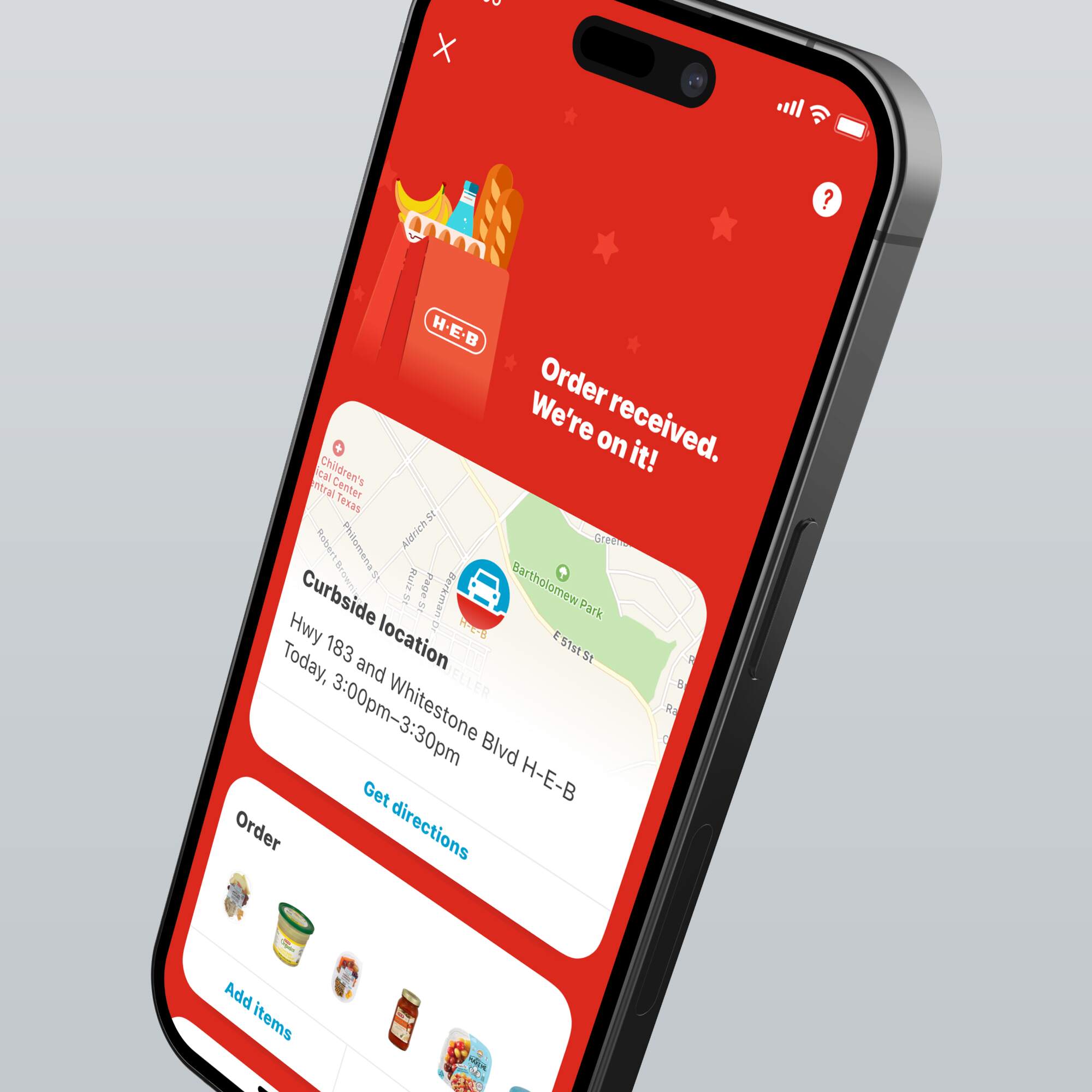 A smartphone displaying the order confirmation screen on the H-E-B app, showing curbside location and order details.