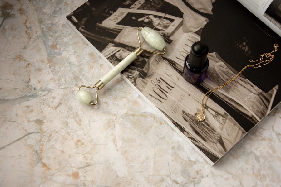A marble still life with a beauty tool, magazine, and delicate jewelry.