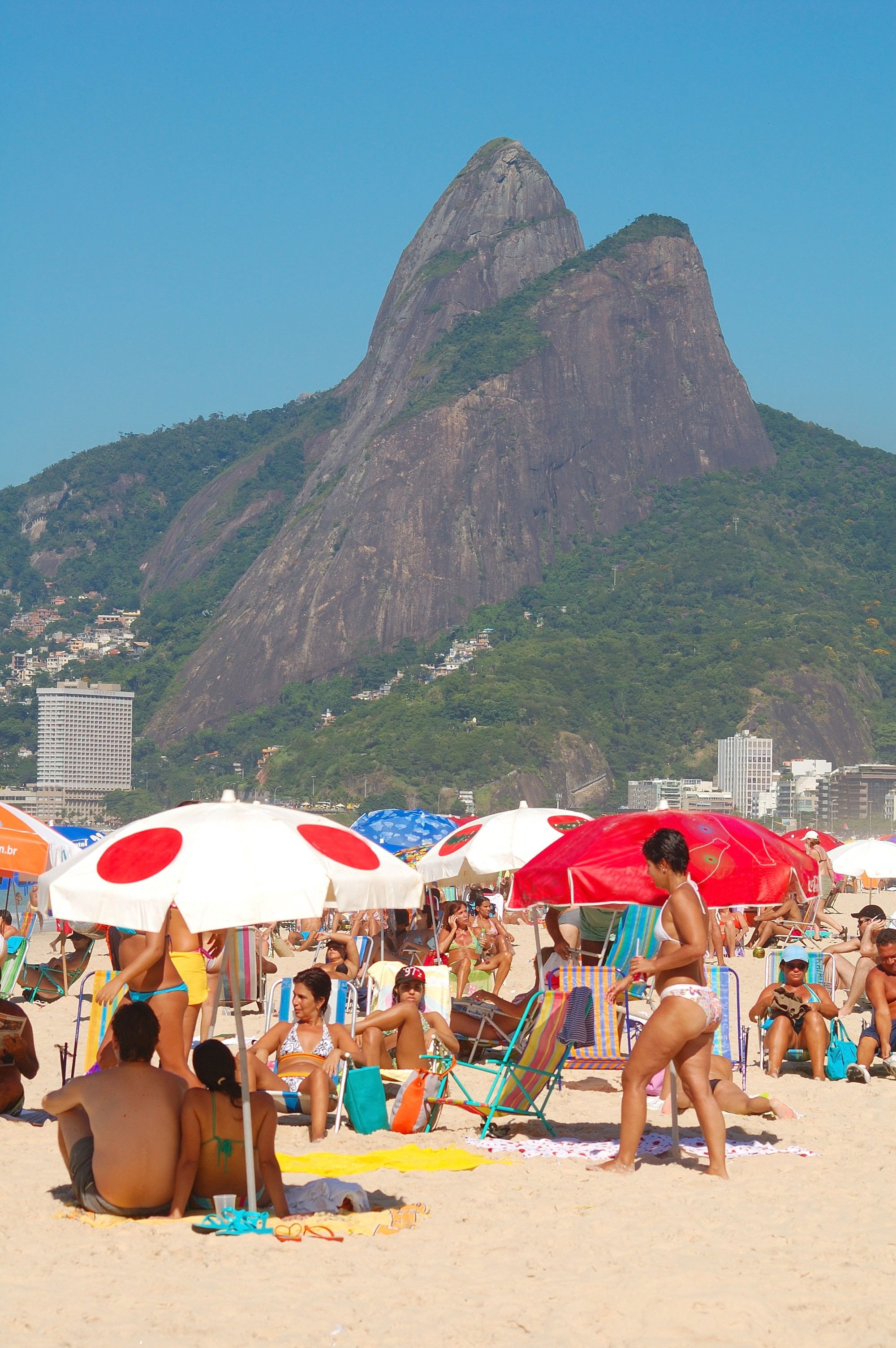 A smiling young man with crossed arms, wearing a plaid shirt and white t-shirt, poses against a dark background.
