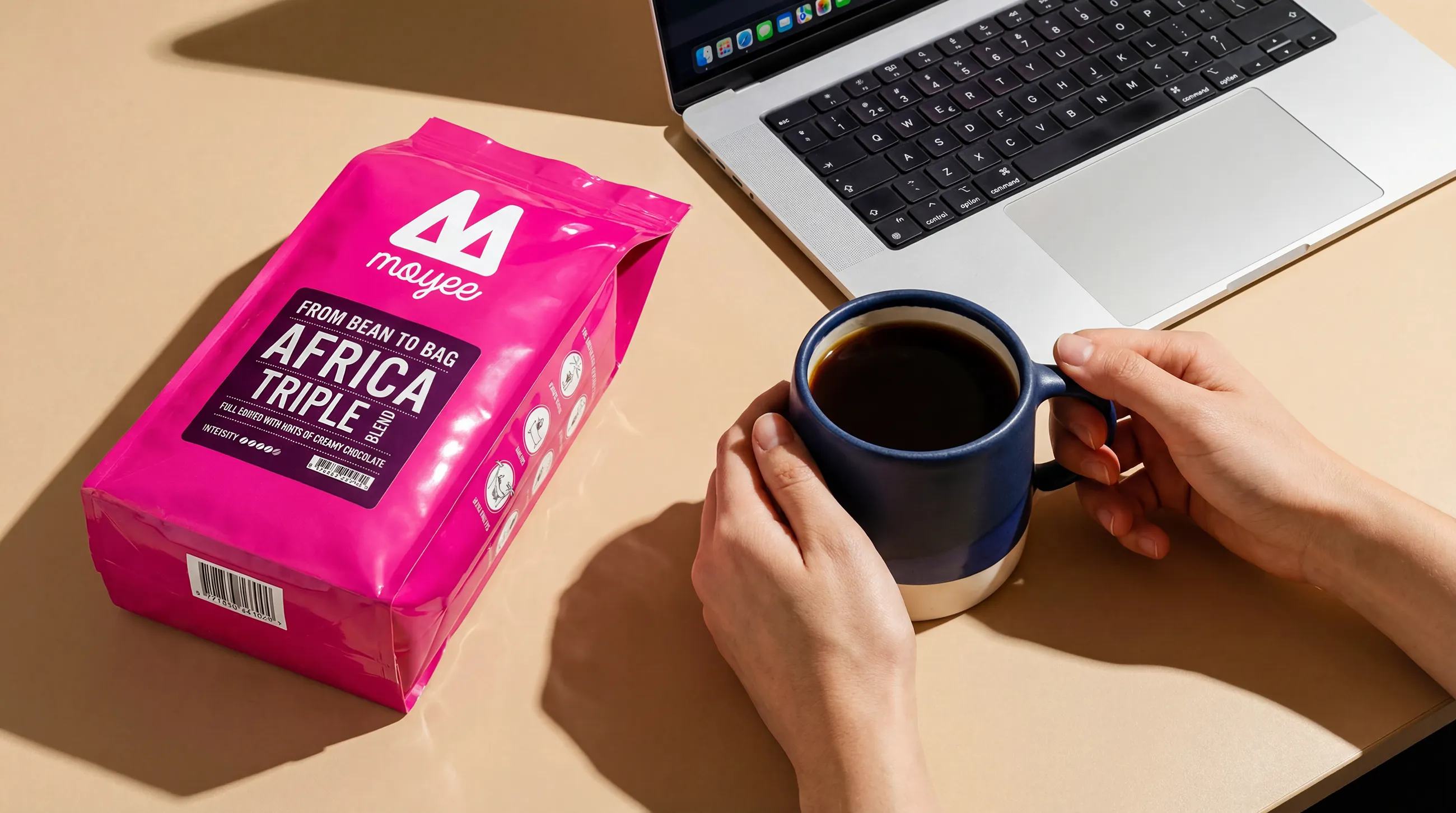 a pink bag of coffee beans and a coffee mug with a laptop
